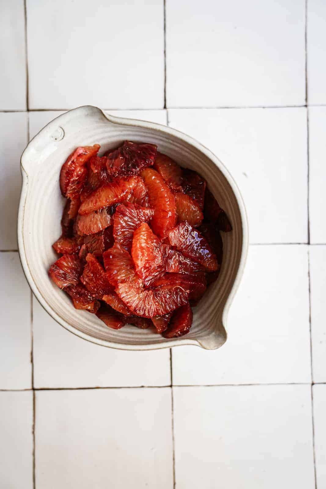 Slices of blood oranges on a white countertop for blood orange salad