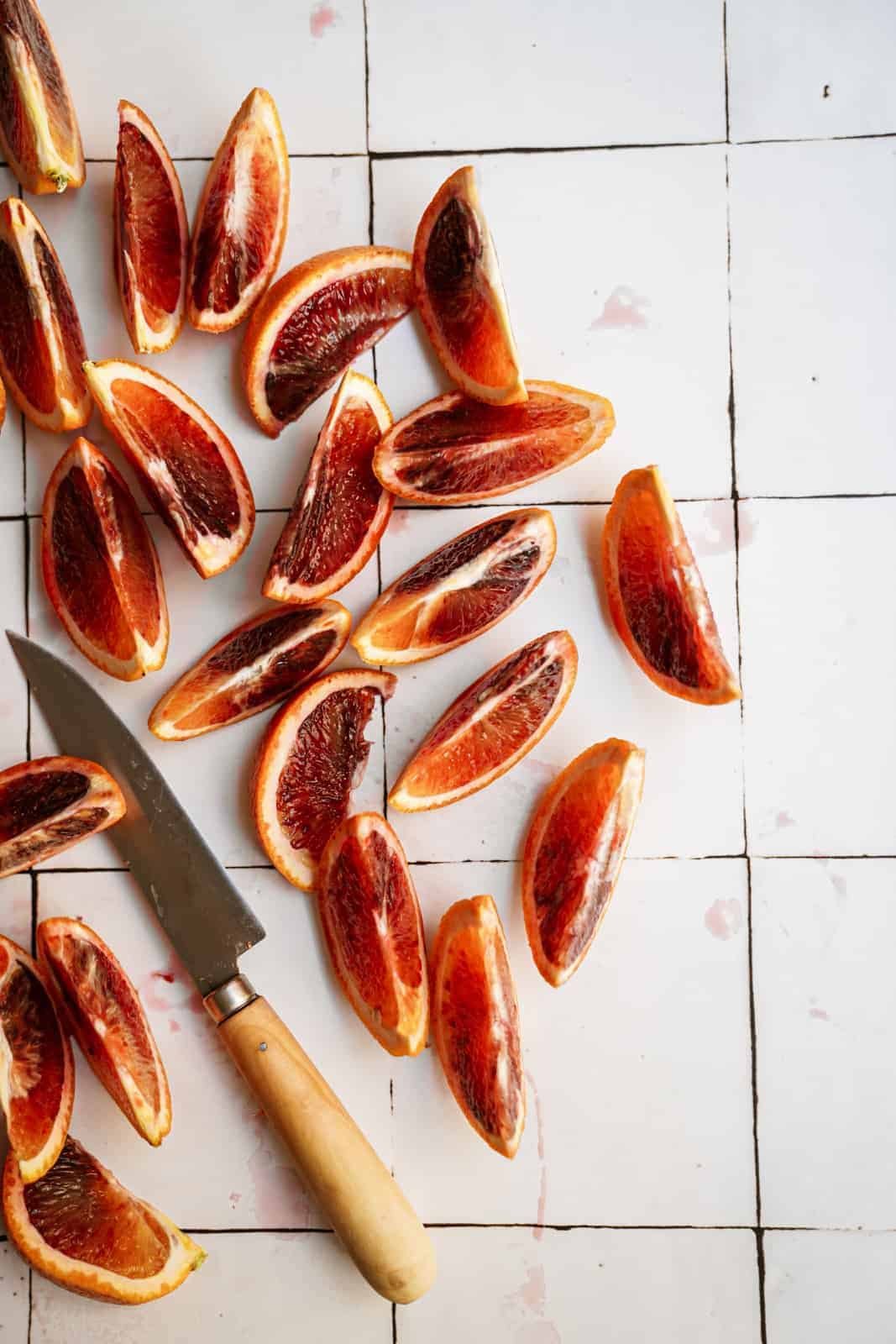 Slices of blood oranges on a white countertop for blood orange salad