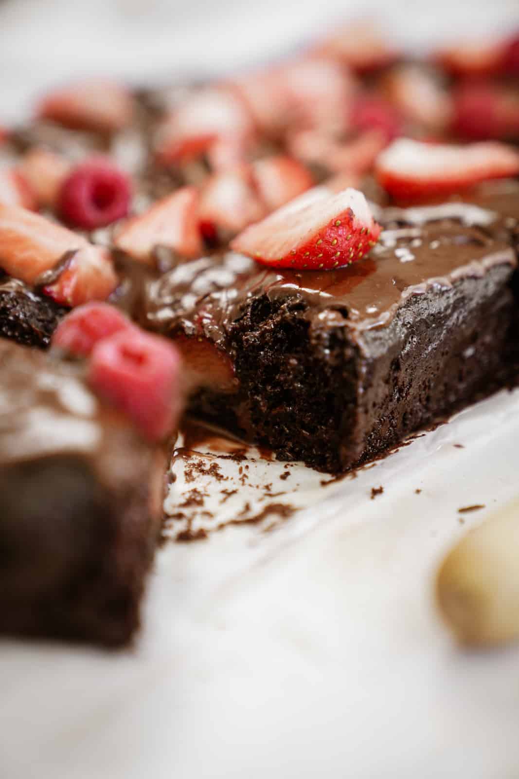 Side angle, close-up of vegan sheet cake on countertop topped with fresh berries