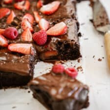 Chocolate Vegan Sheet Cake recipe on countertop cut into squares.