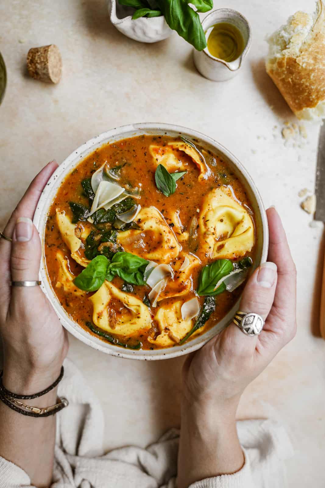 Hands holding bowl of warming vegan tortellini soup 