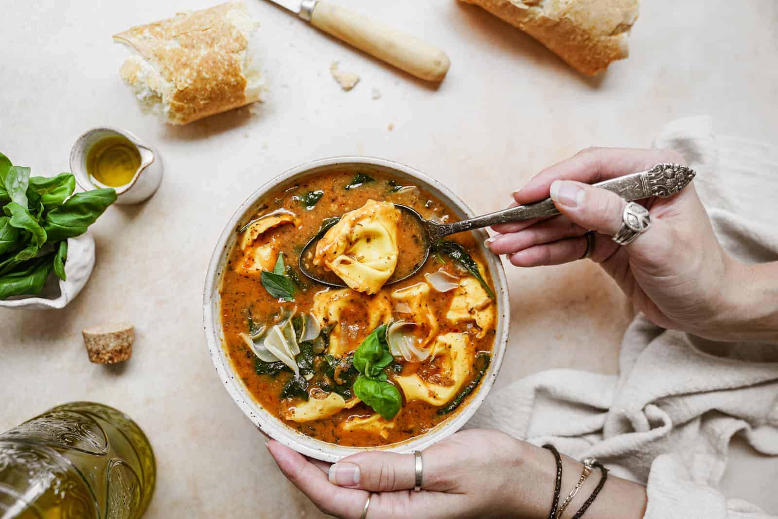 Hand stirring vegan tortellini soup with spoon