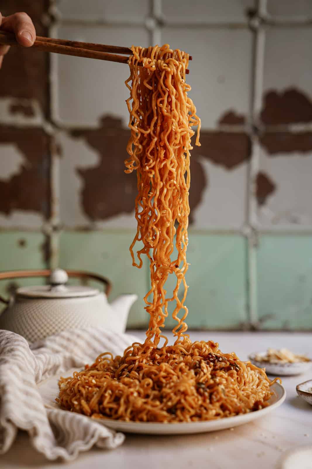 Chopsticks picking up a bunch of Vegan Garlic Noodles off a plate