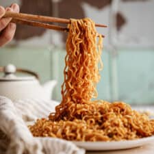 Chopsticks picking up a bunch of Vegan Garlic Noodles off a plate