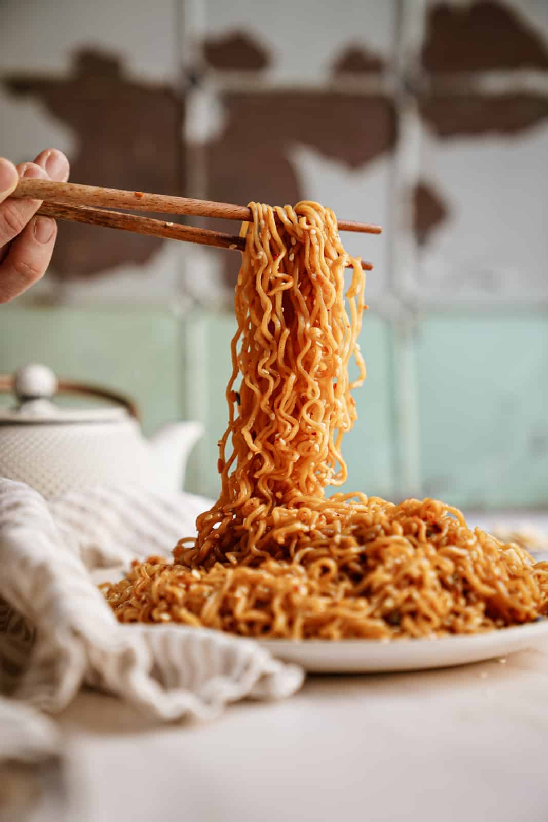 Chopsticks picking up a bunch of Vegan Garlic Noodles off a plate