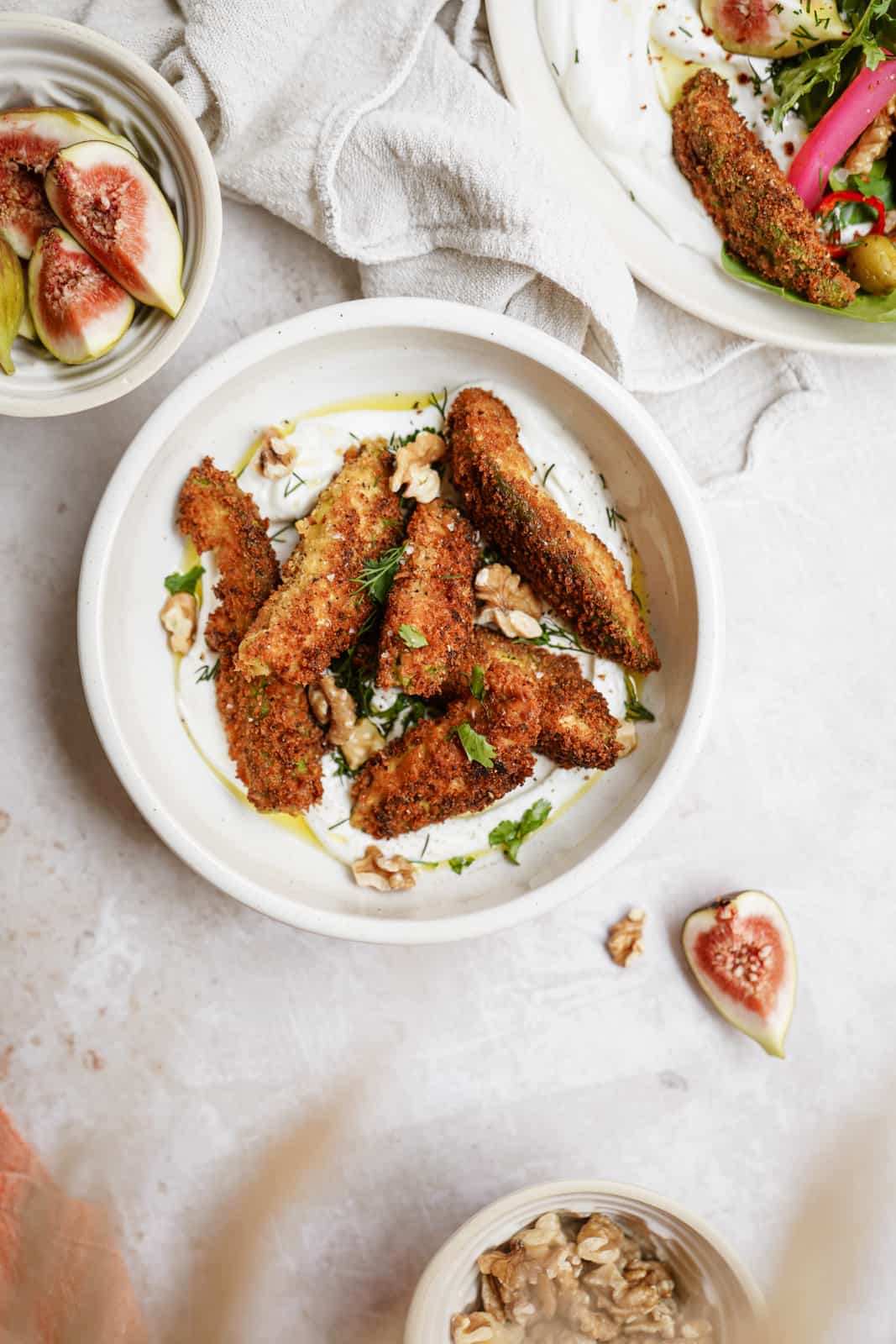 Fried Avocado's on a plate surrounded by fresh salad ingredients.