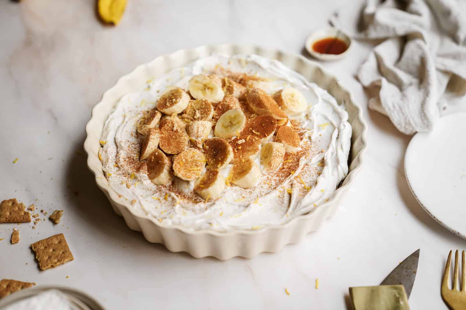 Easy vegan banana cream pie on countertop with fresh bananas on top