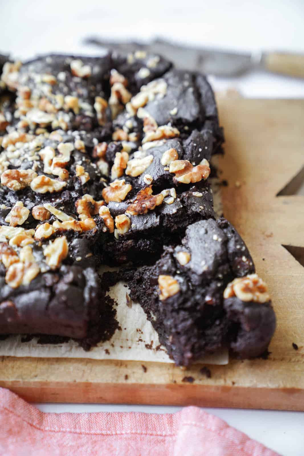 vegan fudge brownies on a cutting board with a piece cut out