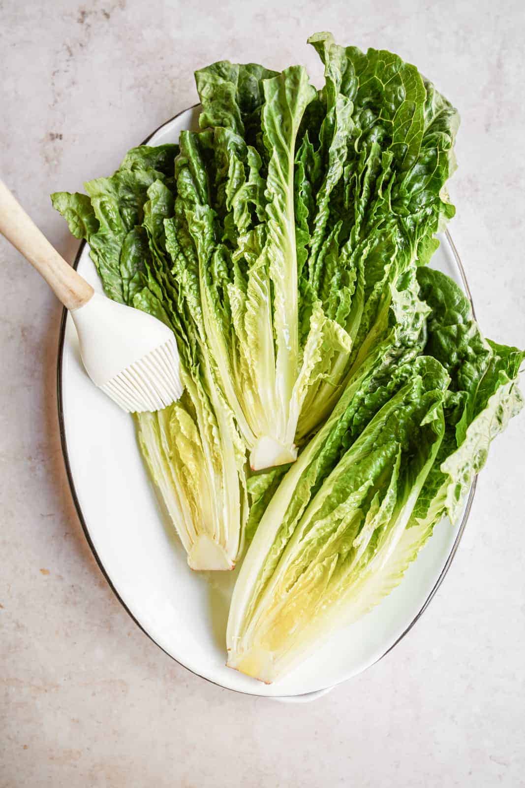 Romaine lettuce being brushed and ready to be grilled