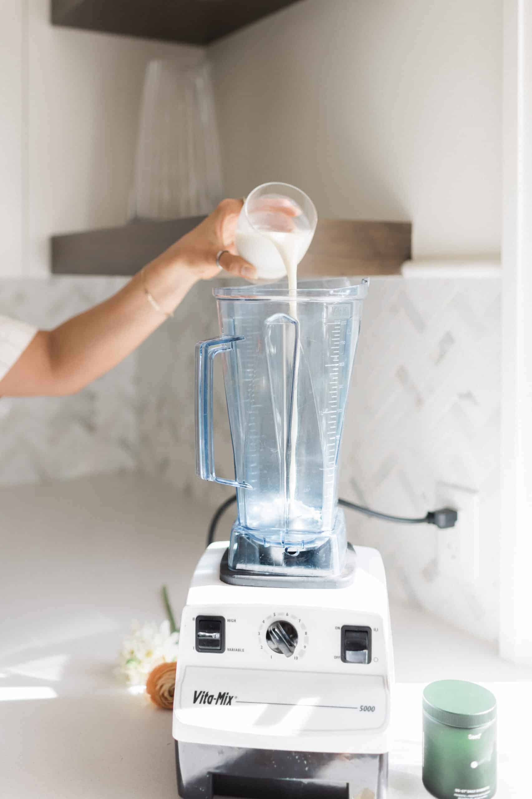 Milk being added to blender for banana berry smoothie