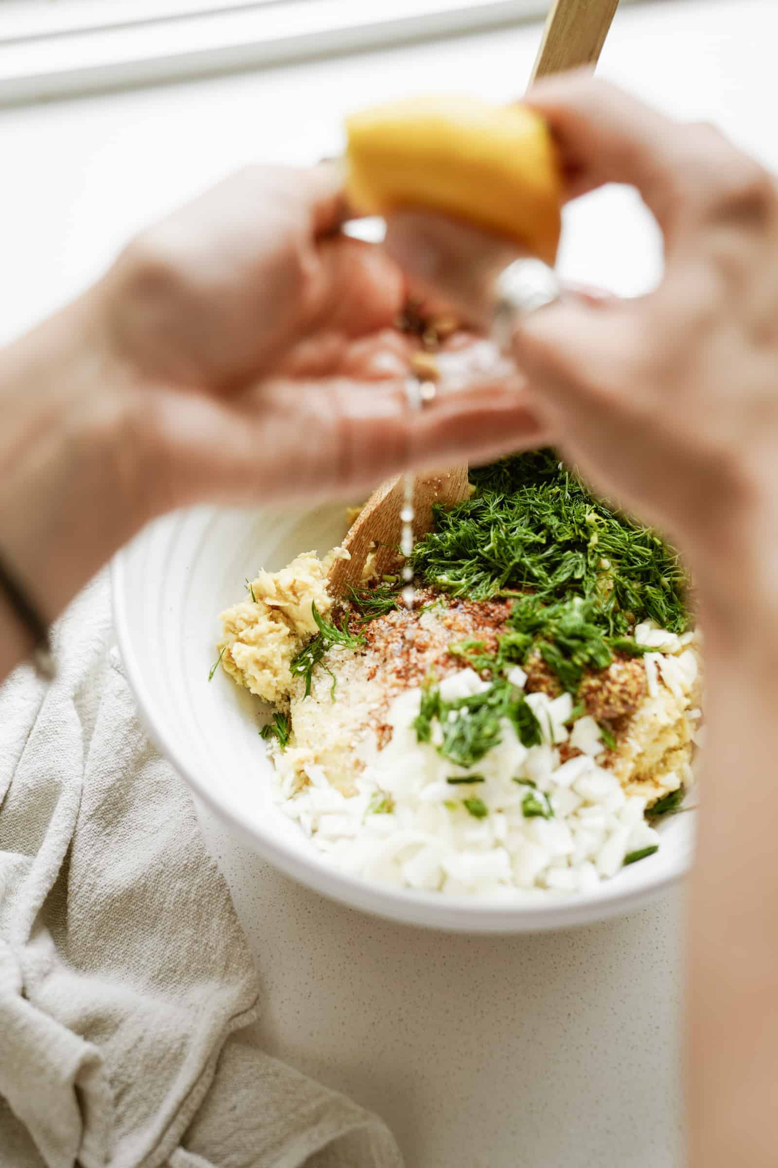 Ingredients being added to a mixing bowl for crab cakes