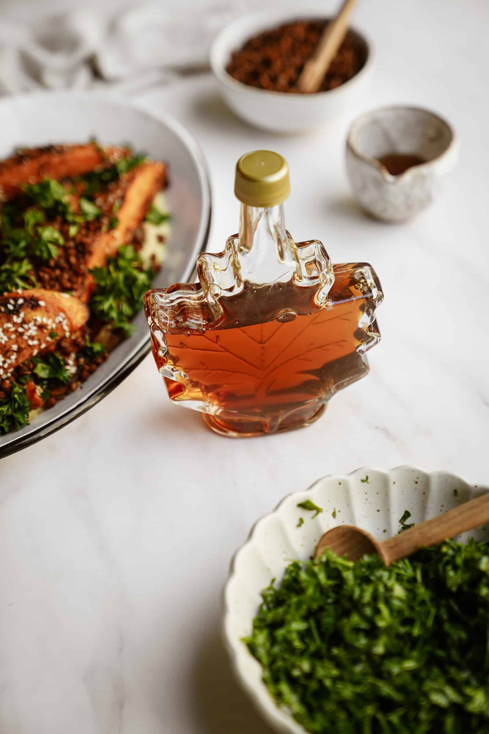 Maple syrup on table around roasted sweet potatoes