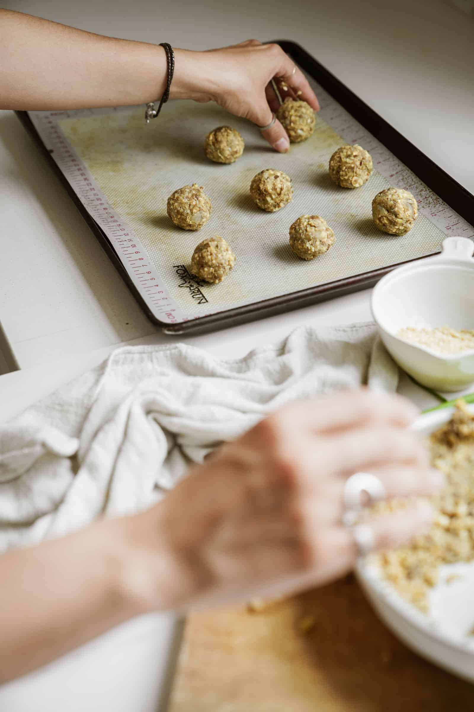 Lentil meatballs being added to a baking tray