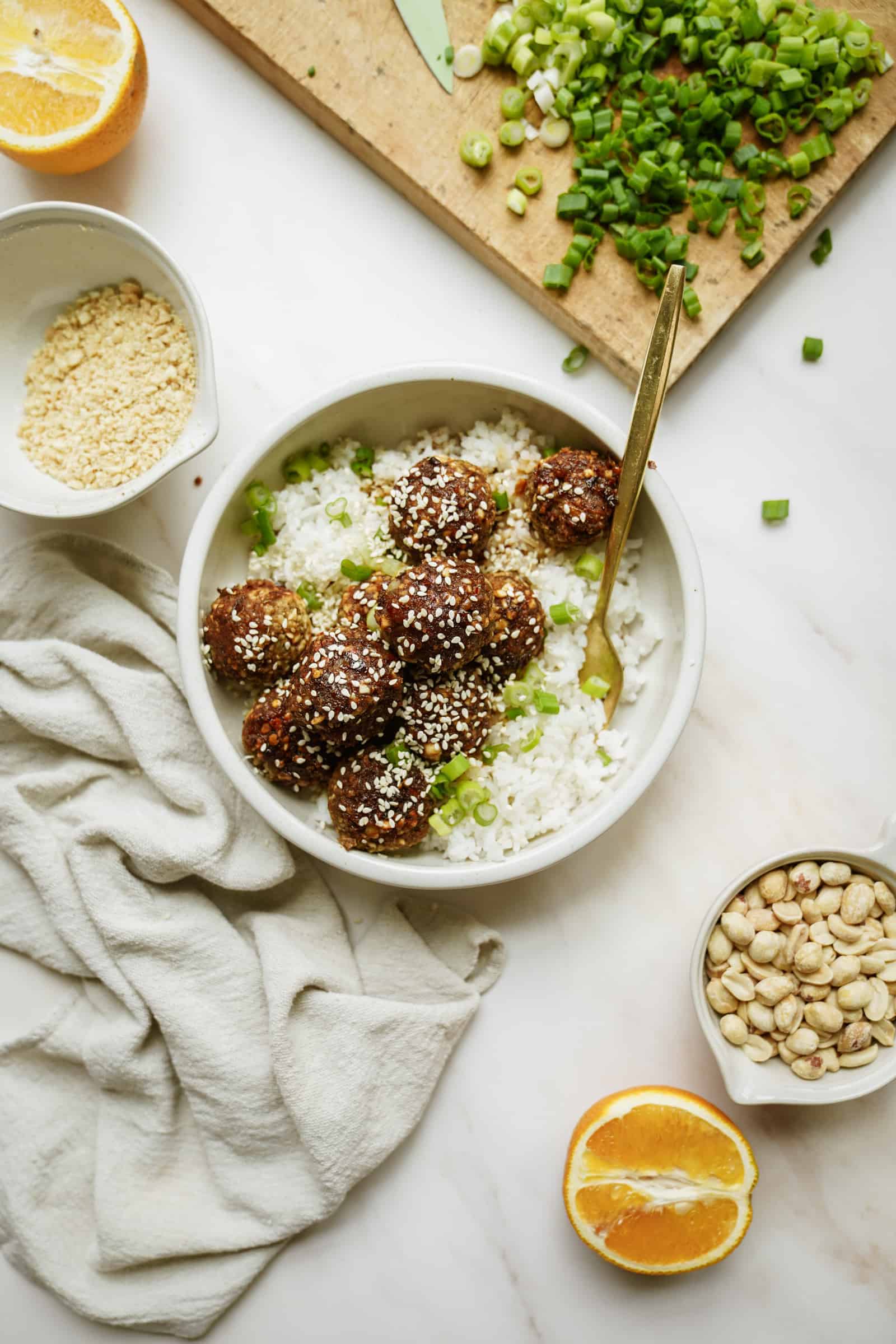 A bowl of lentil meatballs over rice with fresh ingredients