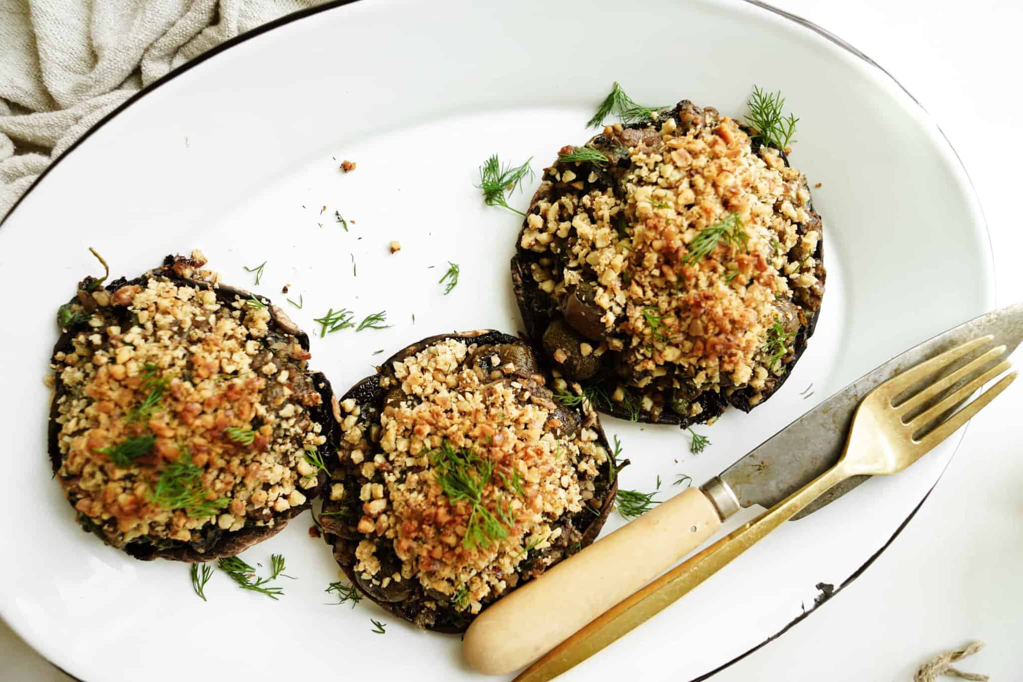 Vegan Stuffed Portobello Mushrooms on a serving plate with a fork and knife