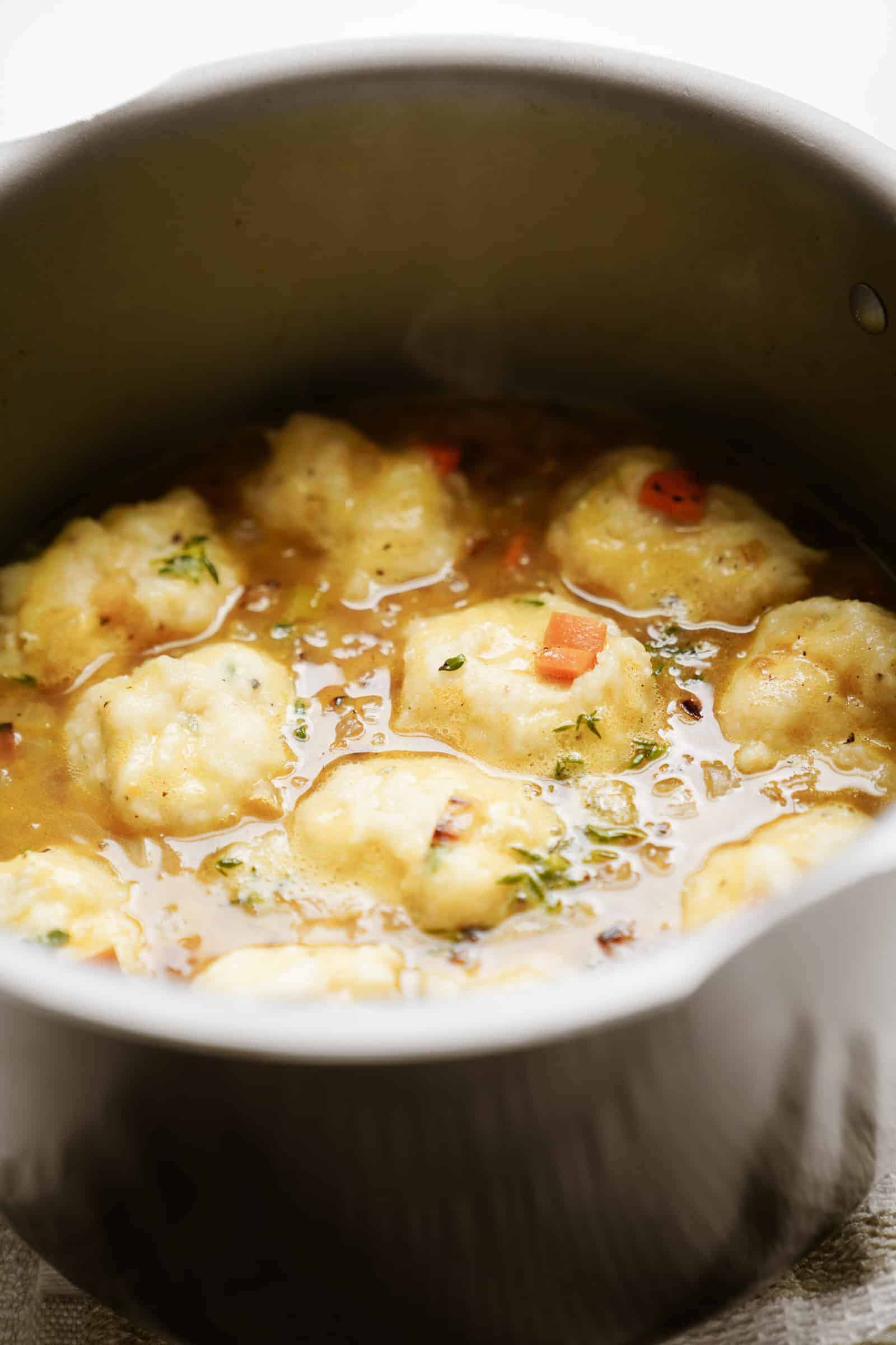 Vegan dumplings in a pot of soup cooking