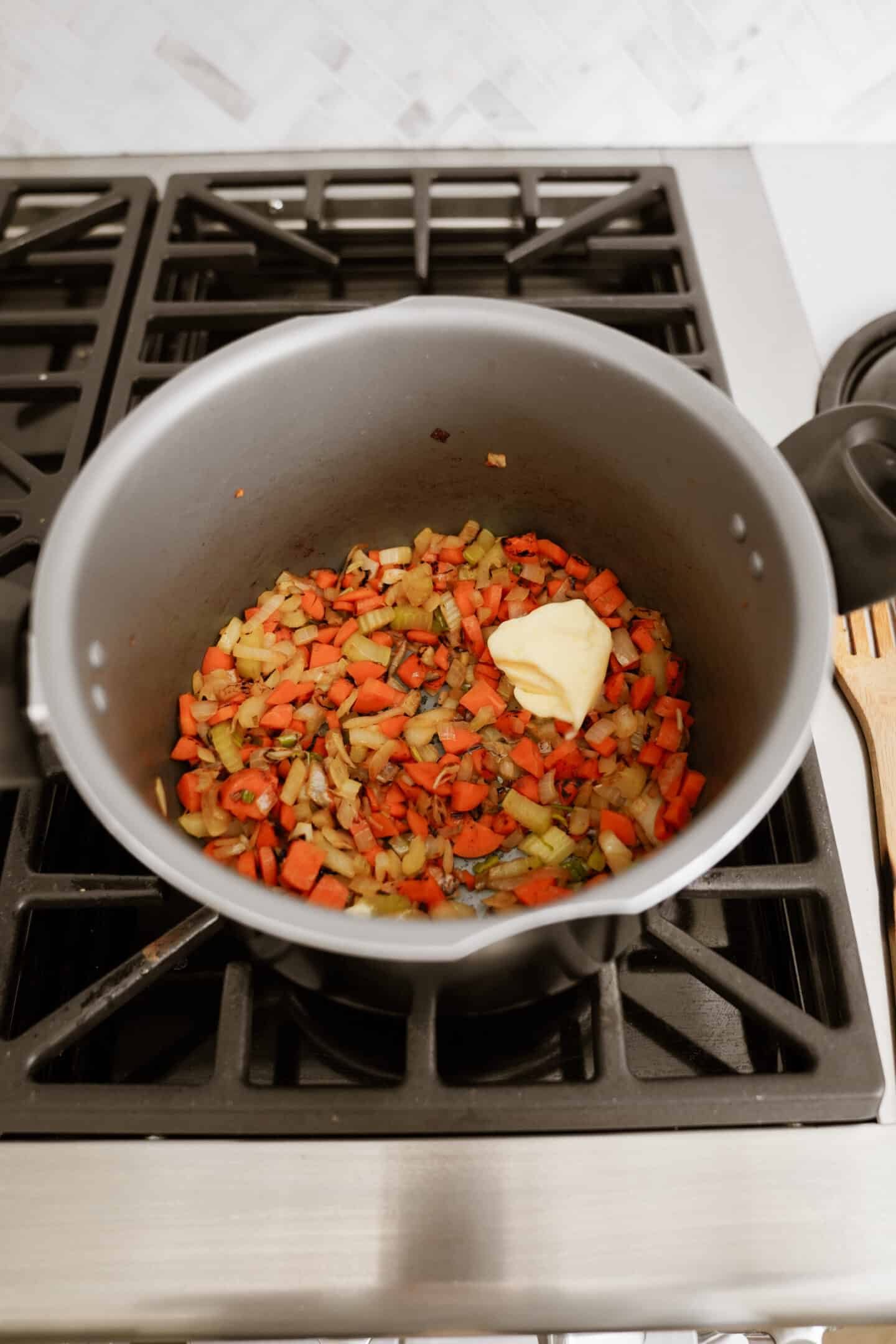 Butter added to a pot of vegetables on a stove