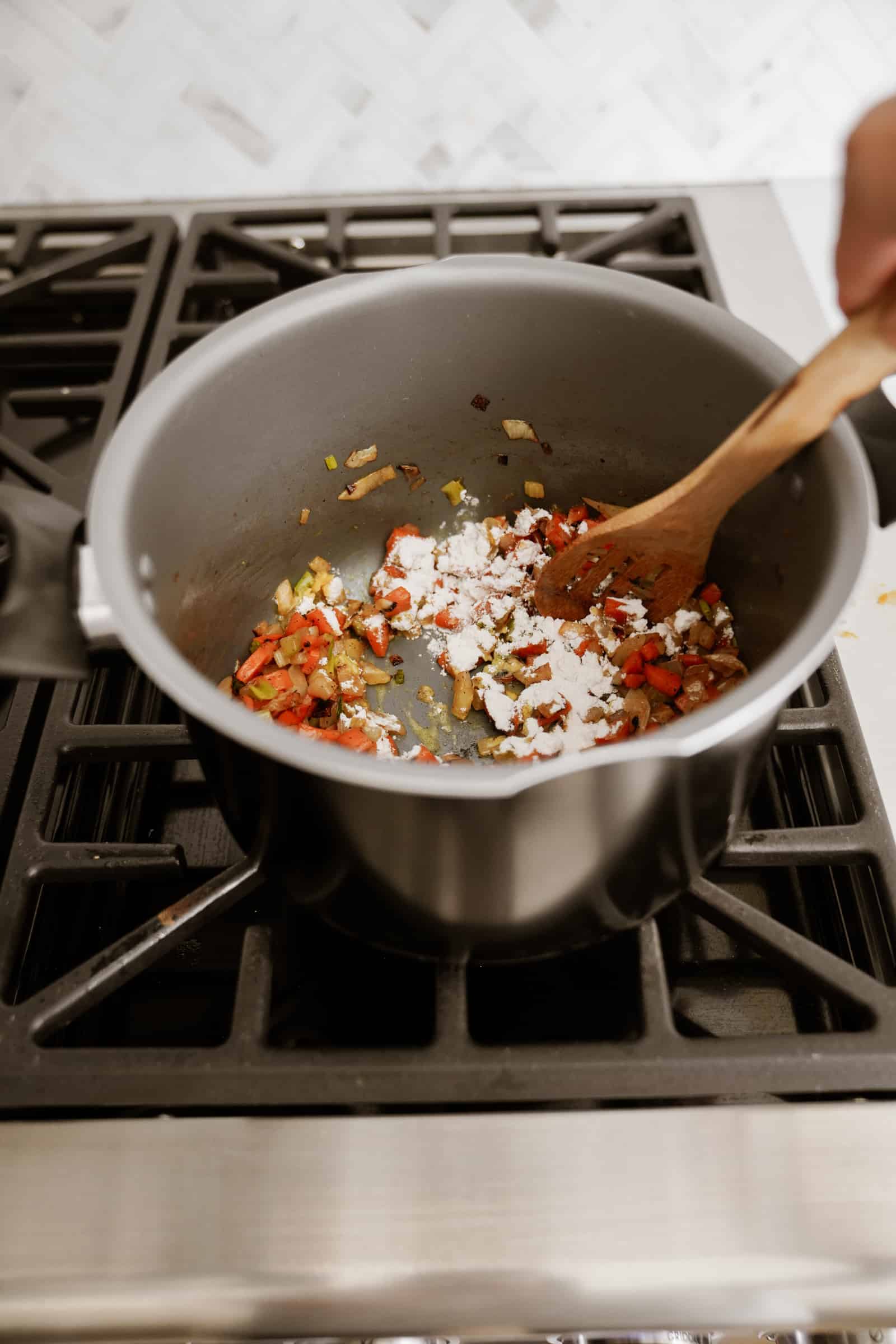 Flour added to a pot with vegetables