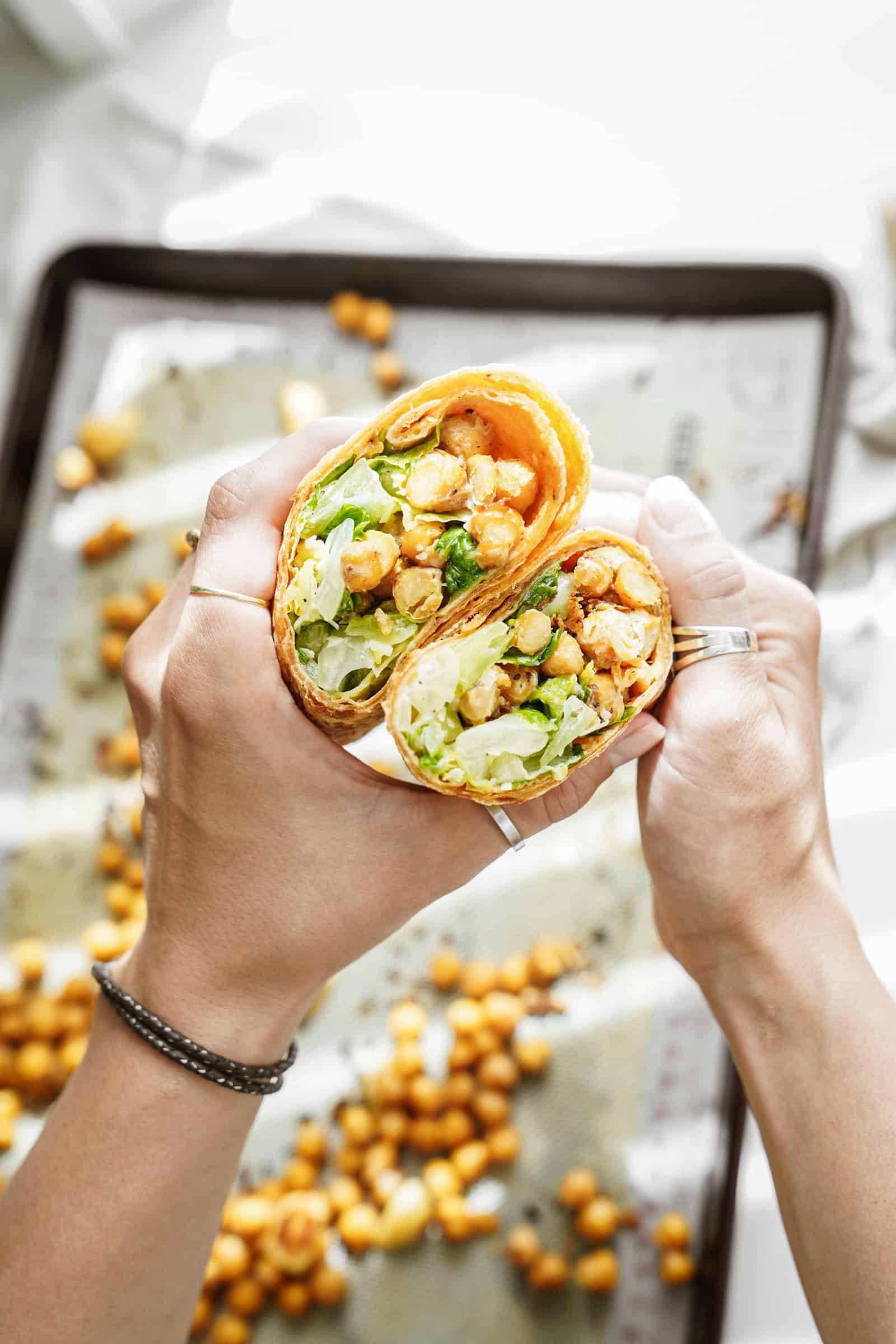 chickpea caesar salad wrap open and being held by 2 hands