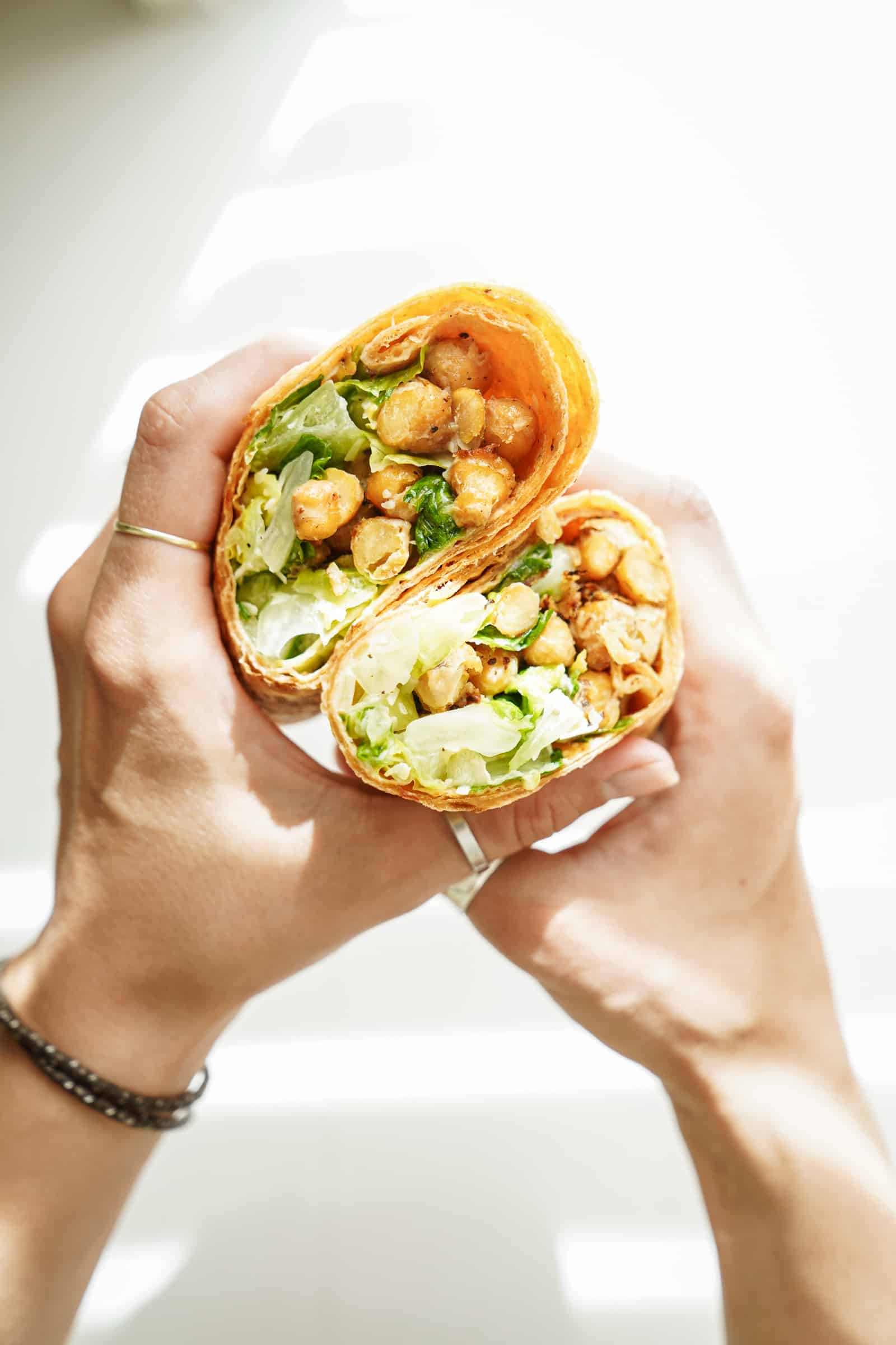 chickpea caesar salad wrap open and being held by 2 hands