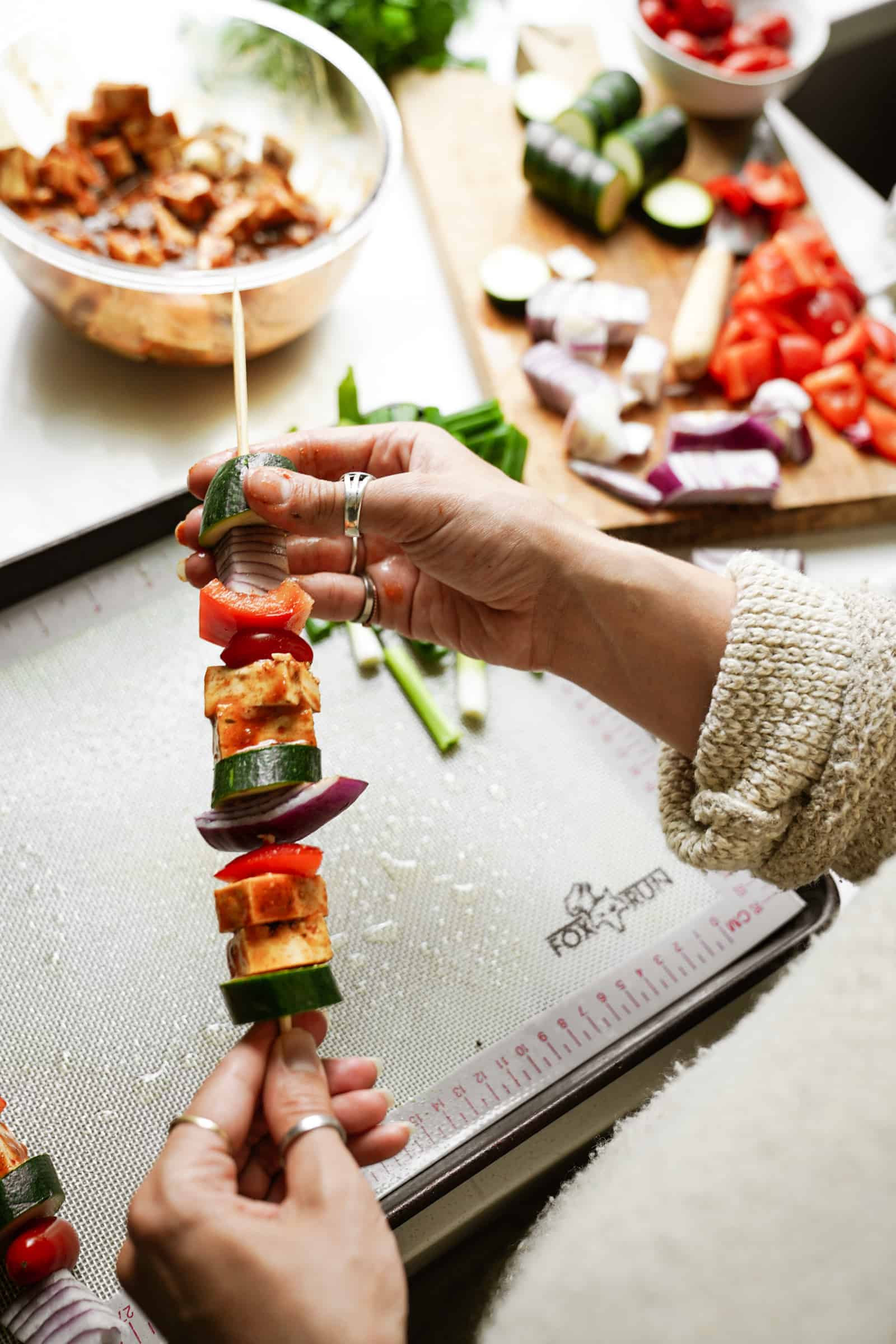 Veggies and tofu being put on skewers for Marinated Tofu and Vegetable Skewers