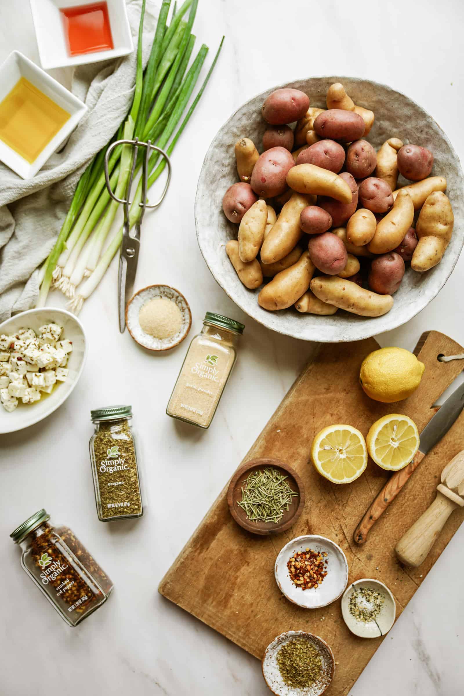 Ingredients on table and cutting board for Greek Potato Salad