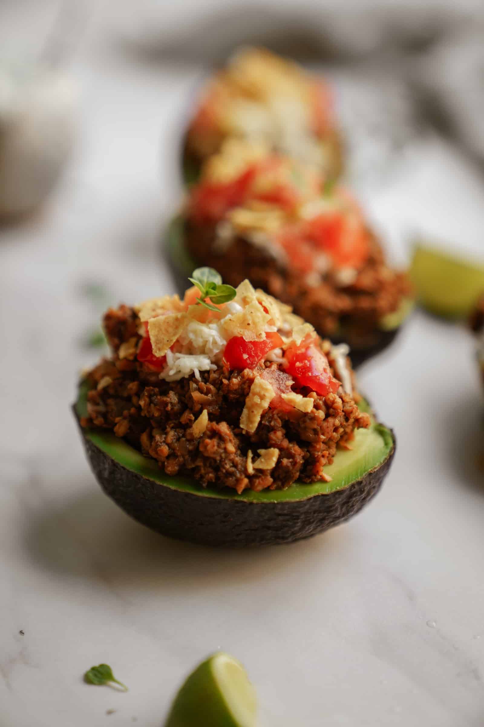 Line-up of stuffed avocados with taco meat and taco toppings