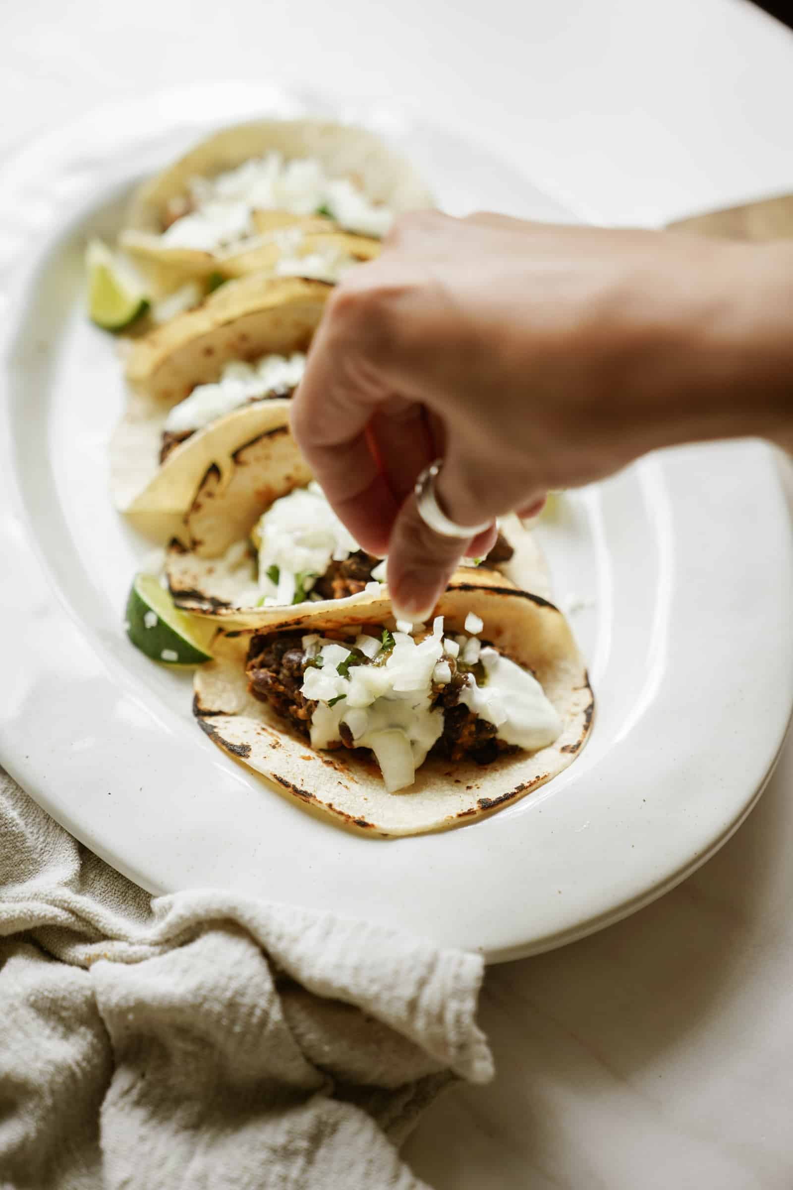 Toppings being added to Vegetarian Black Bean Tacos