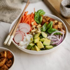 Crispy tofu noodle bowl on counter with chopsticks