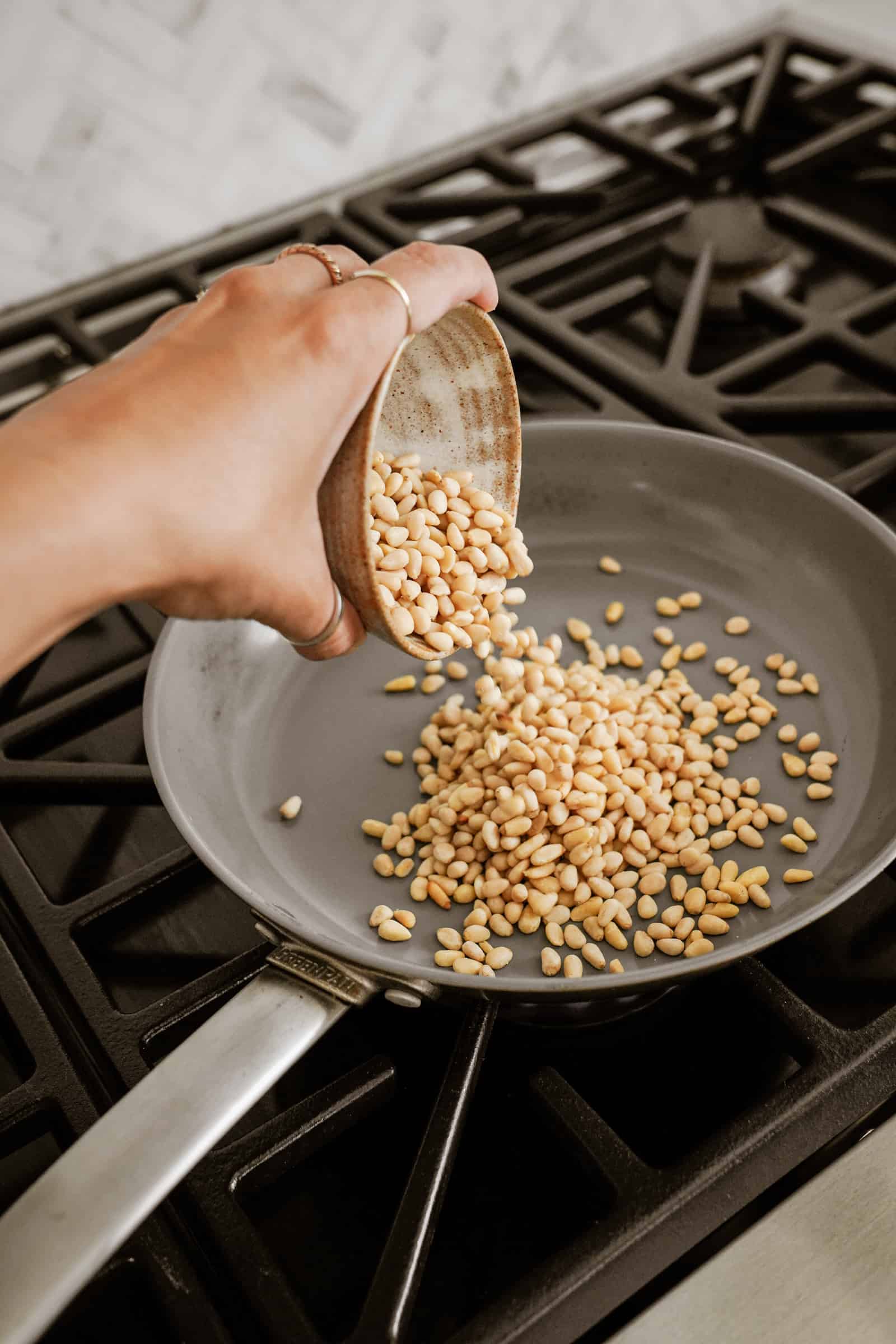 Toasting pine nuts in a pan on a stove