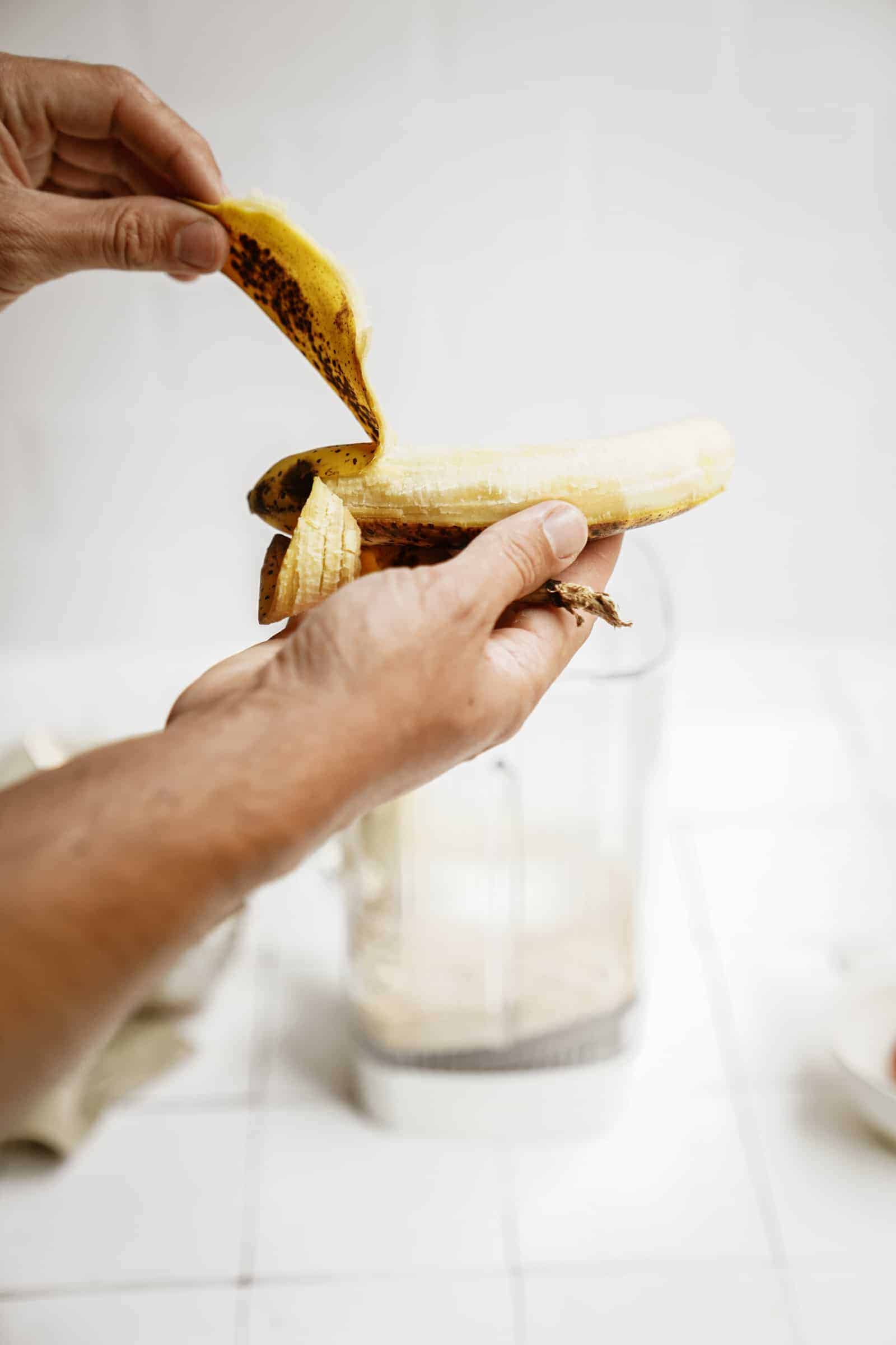 Banana being added into a blender for peanut butter banana pancakes