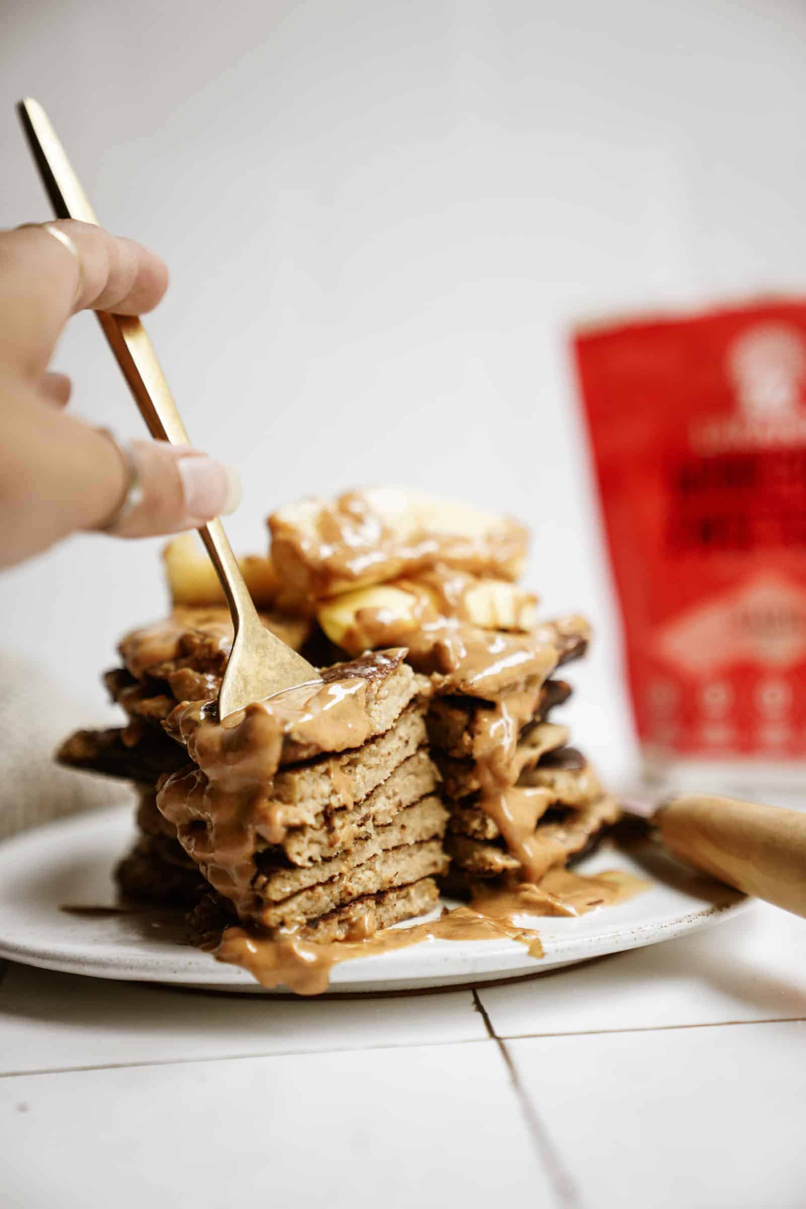 Stack of peanut butter banana pancakes with fork stabbing them