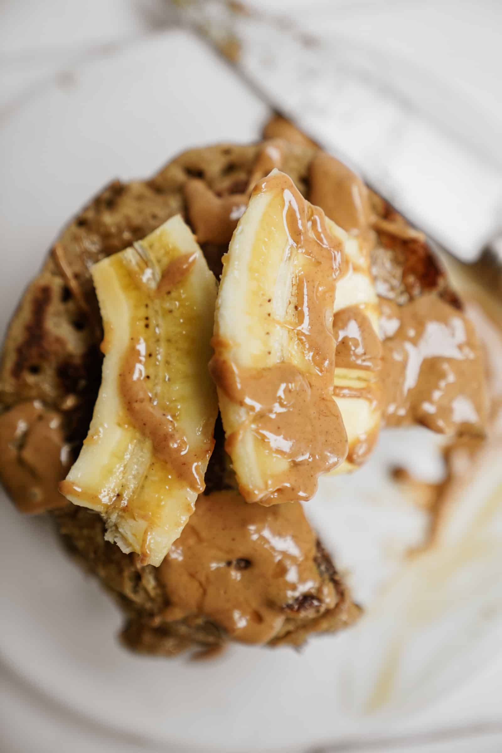 Stack of peanut butter banana pancakes with fresh bananas on top