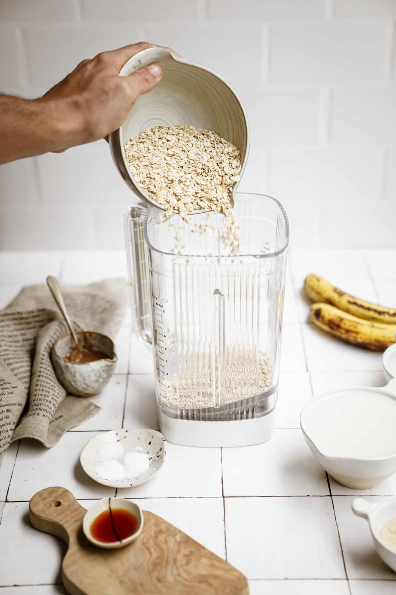 Oats being added into a blender for peanut butter banana pancakes