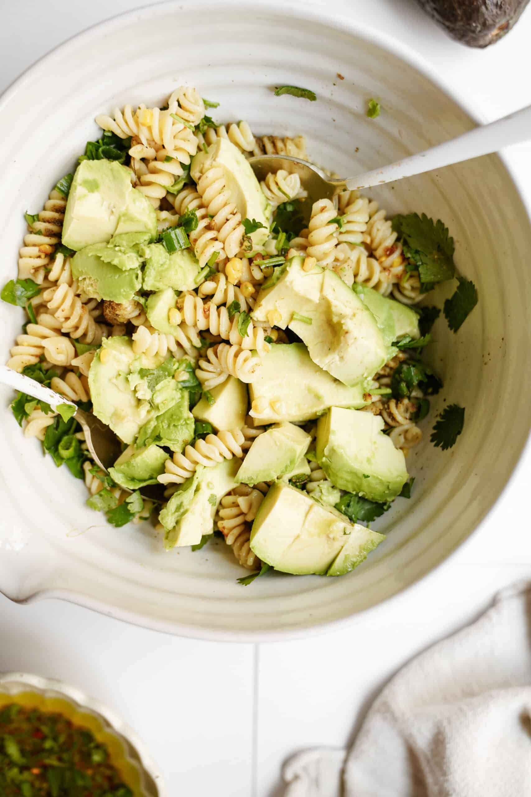 All ingredients for avocado pasta salad mixed in bowl