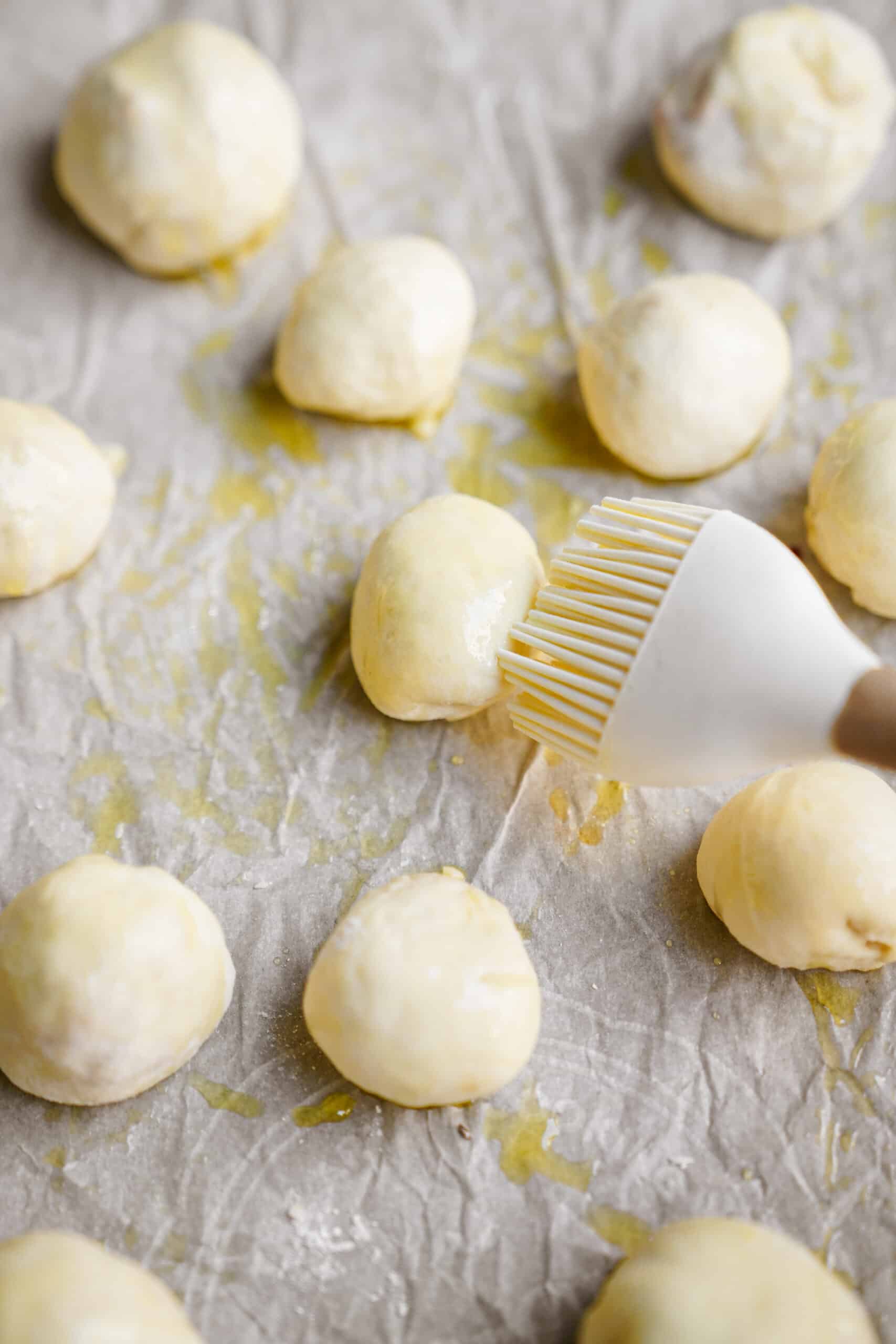 Pizza pockets being brushed with olive oil