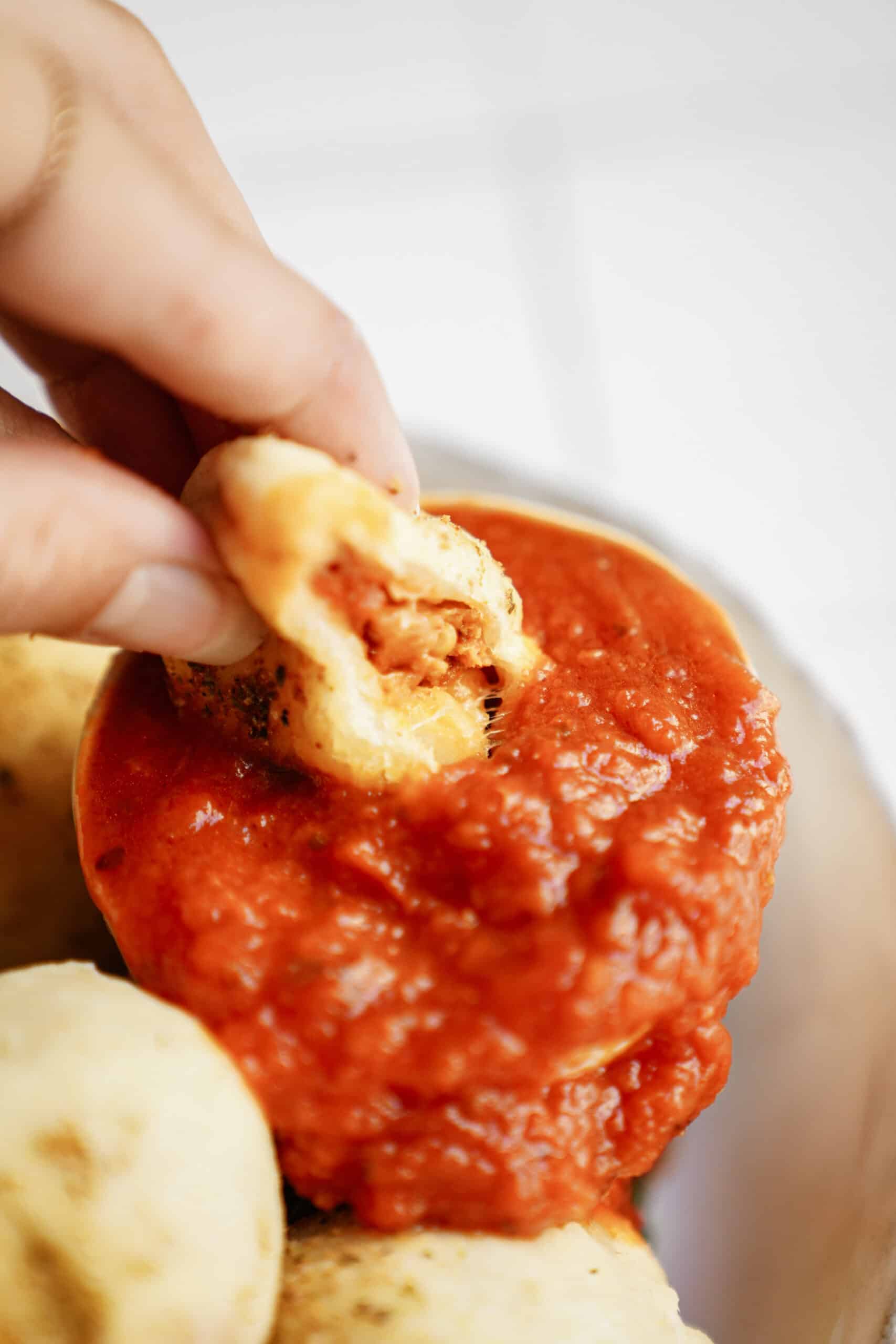 Dipping homemade pizza pocket into dip