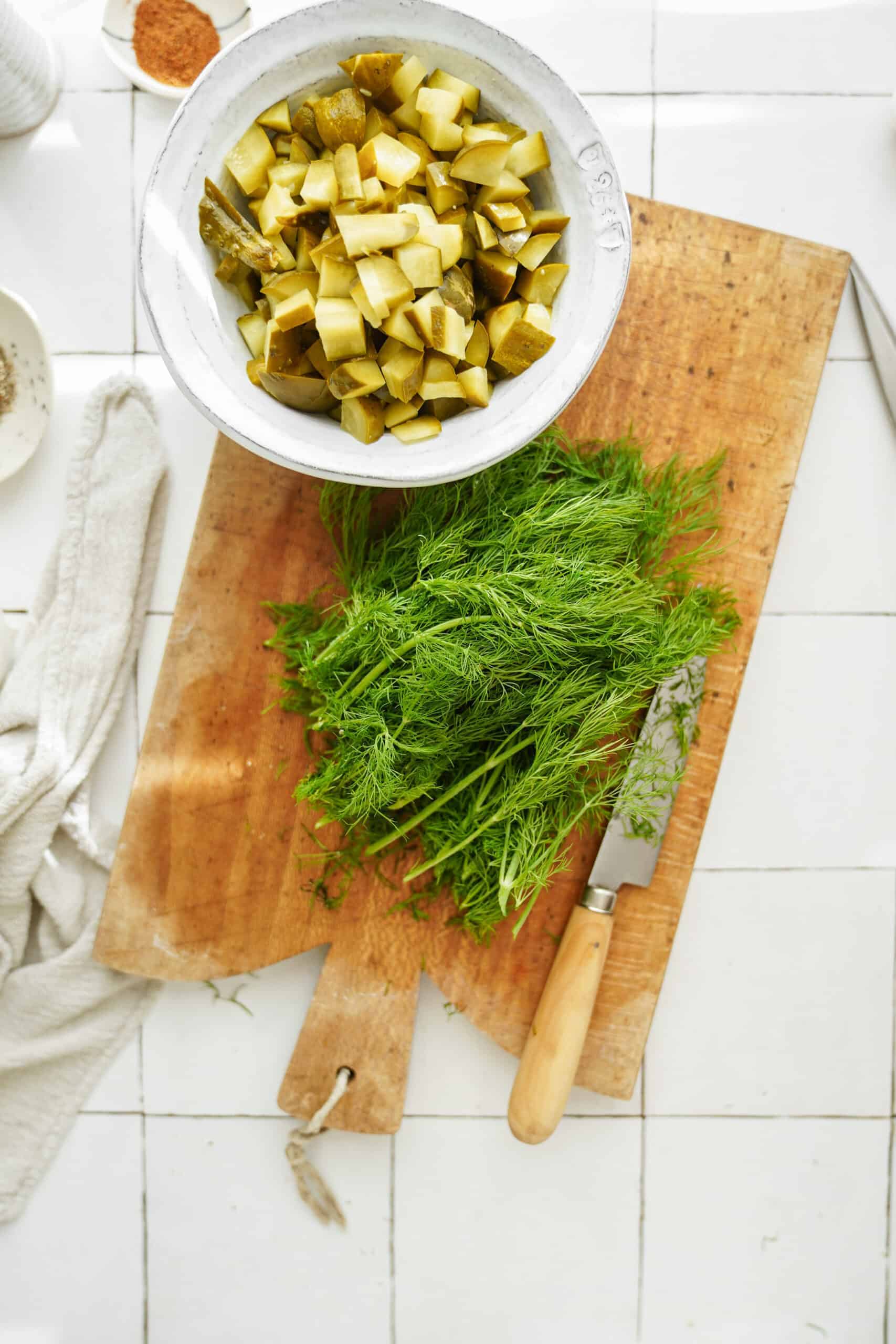 Fresh dill and dill pickles on cutting board