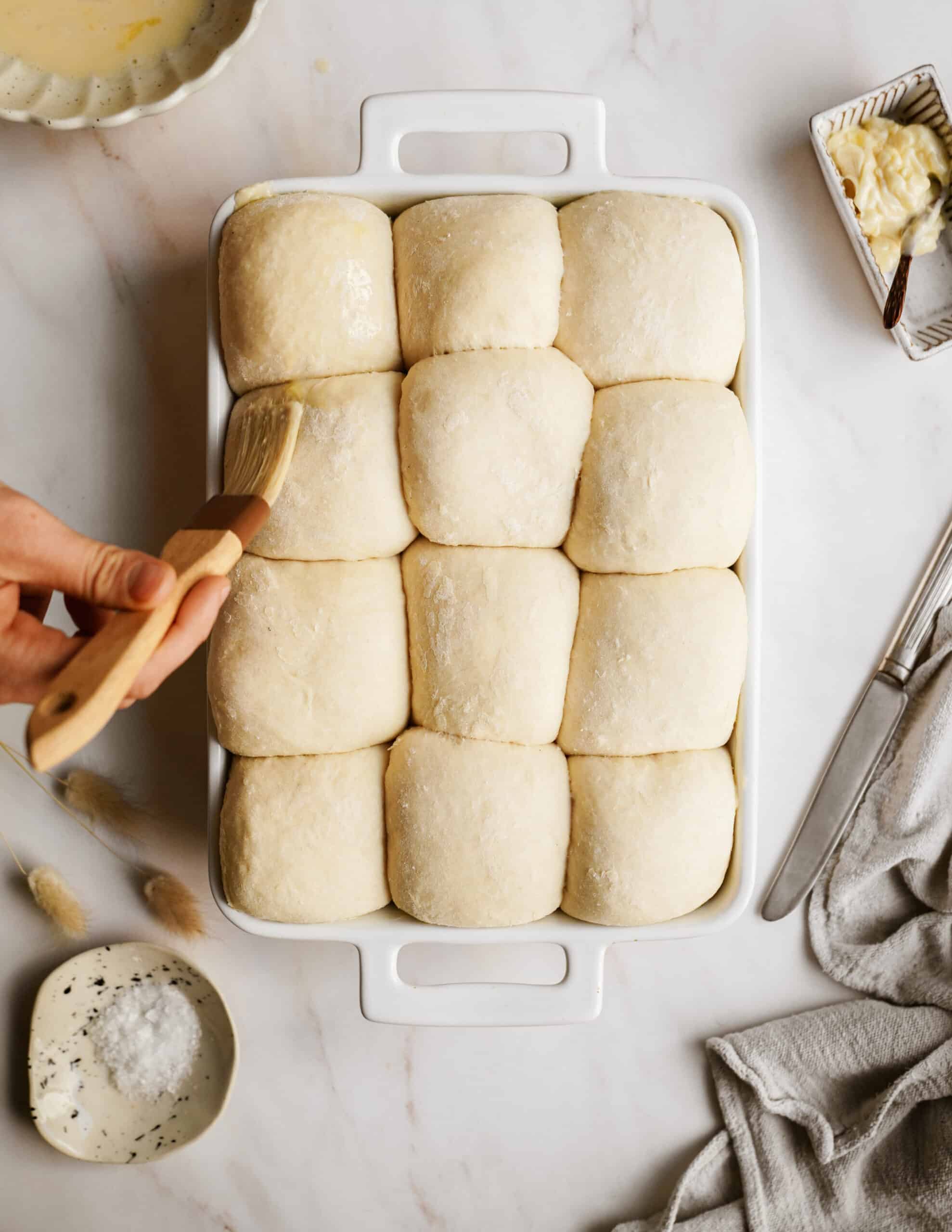 Dinner roll recipe being brushed with butter