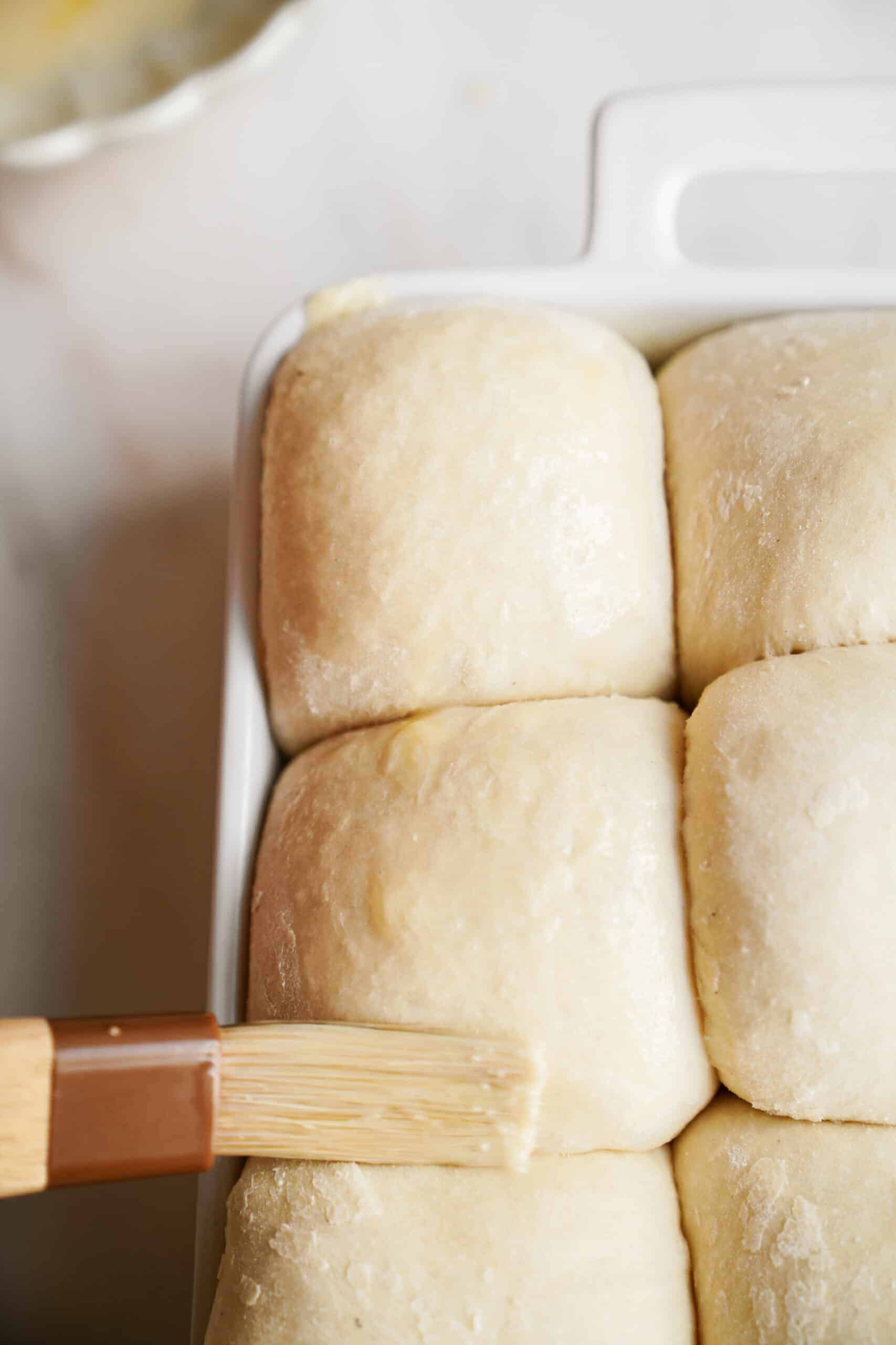 Dinner roll recipe being brushed with butter