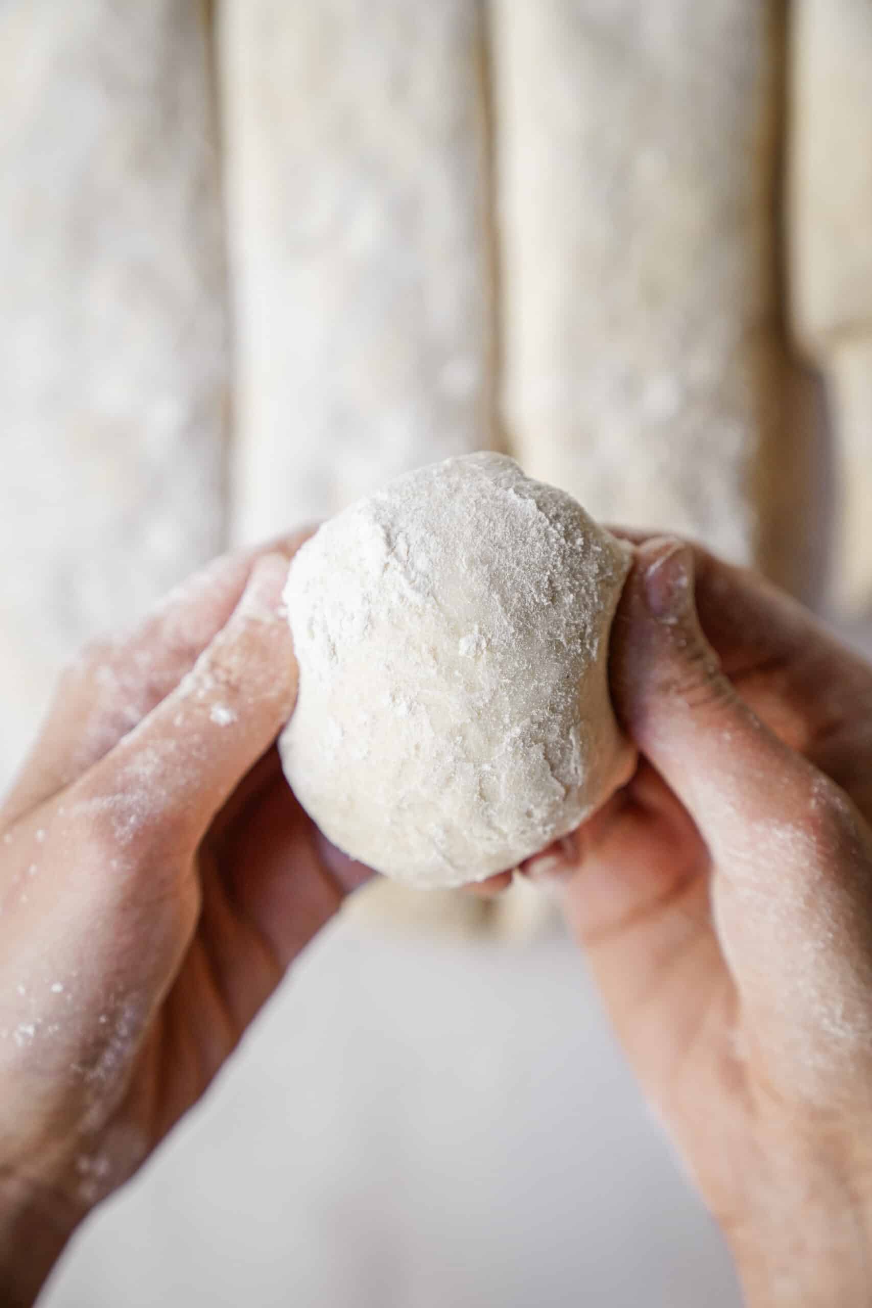 Dough being rolled into dinner rolls