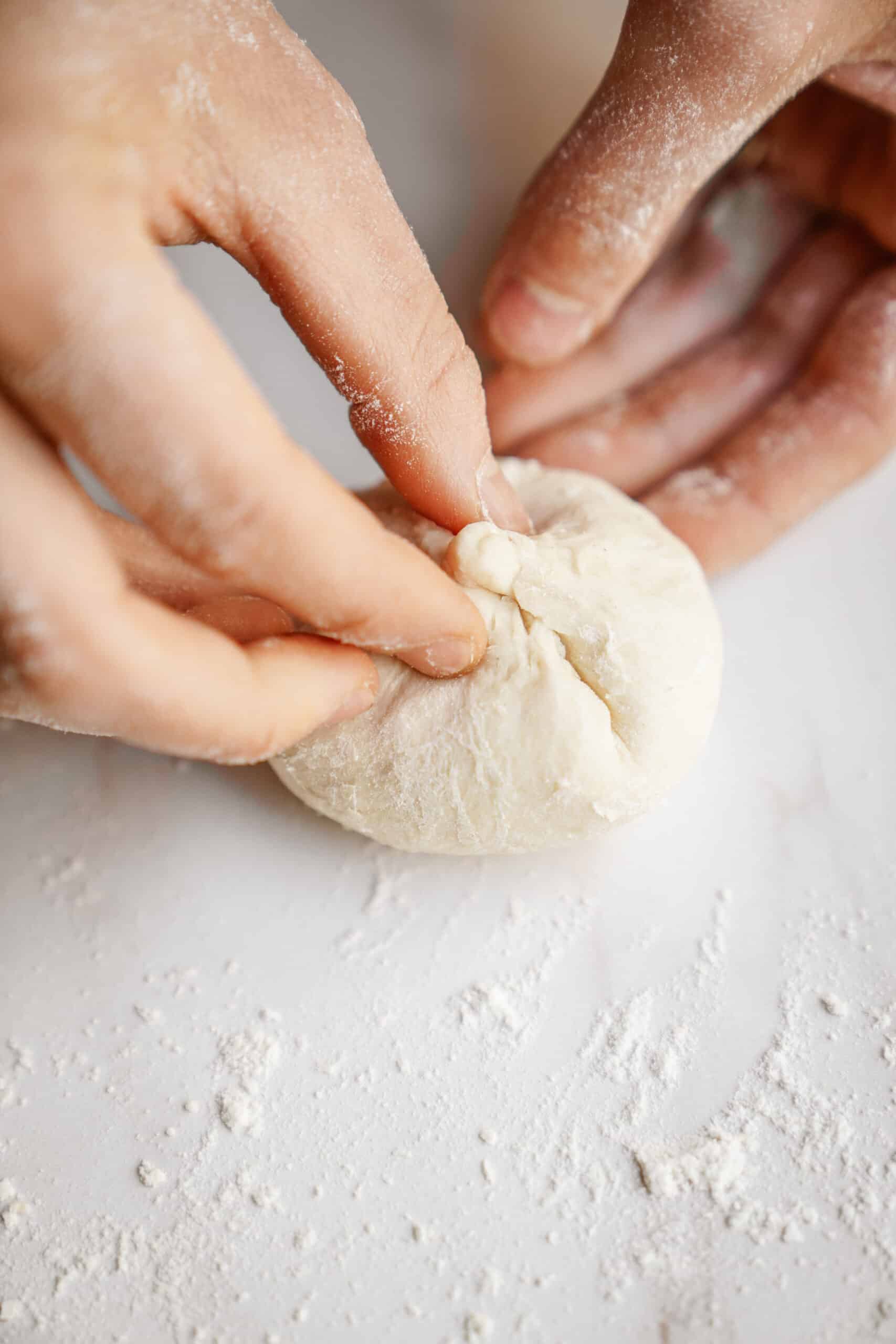 Dough being rolled into dinner rolls