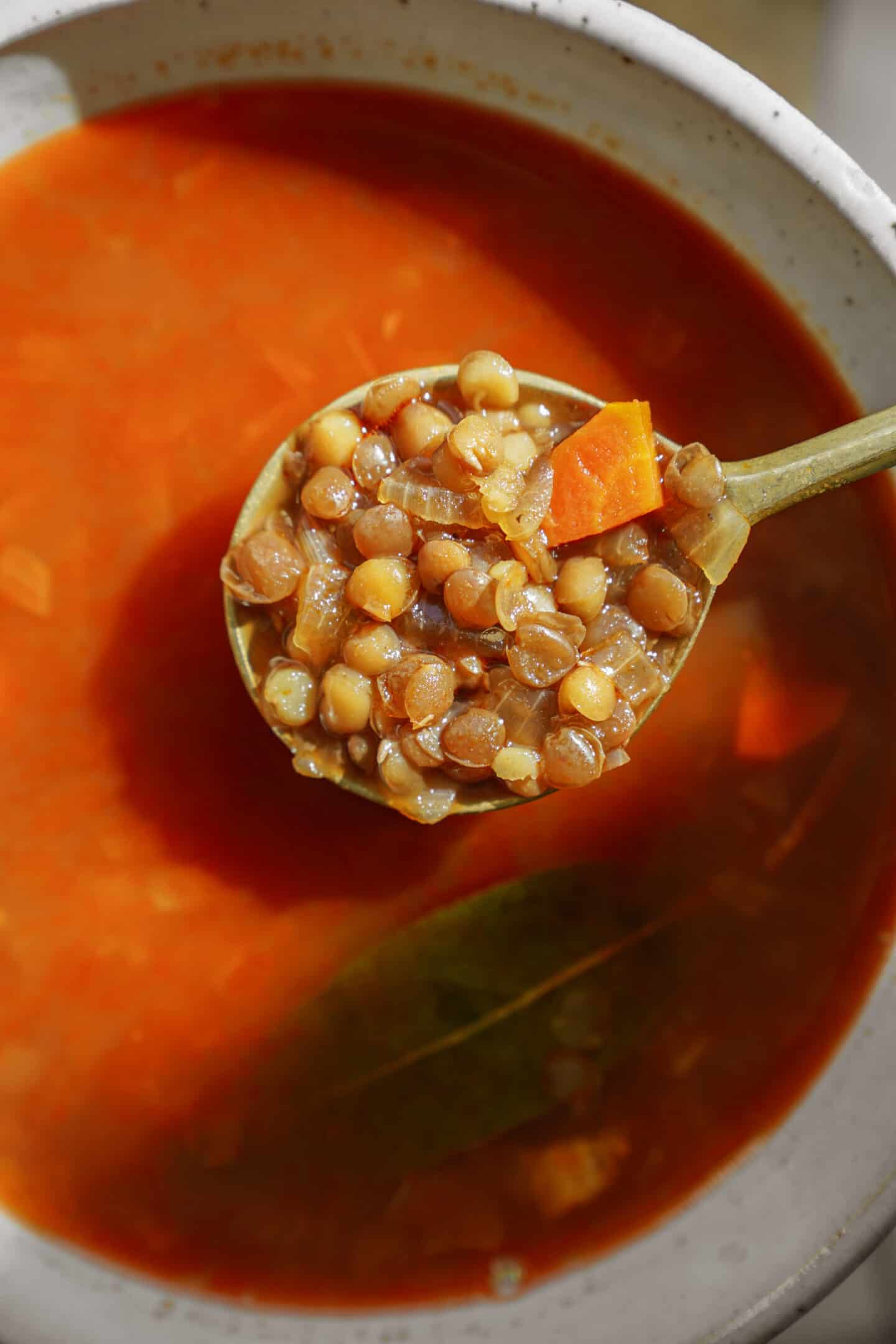 Greek lentil soup in a bowl with a spoon taking a big scoop out