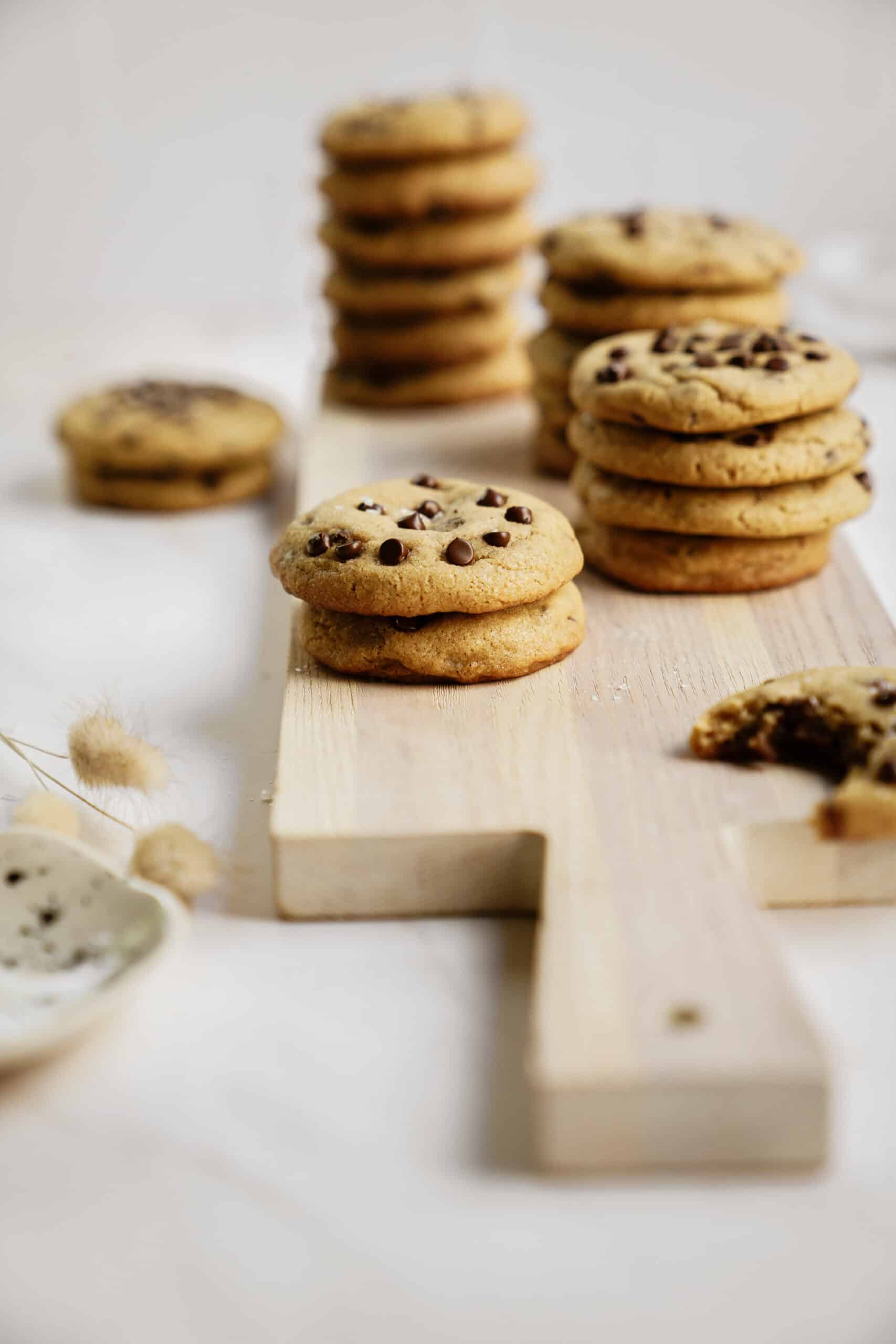 Homemade chocolate chip cookies stacked on a cutting board