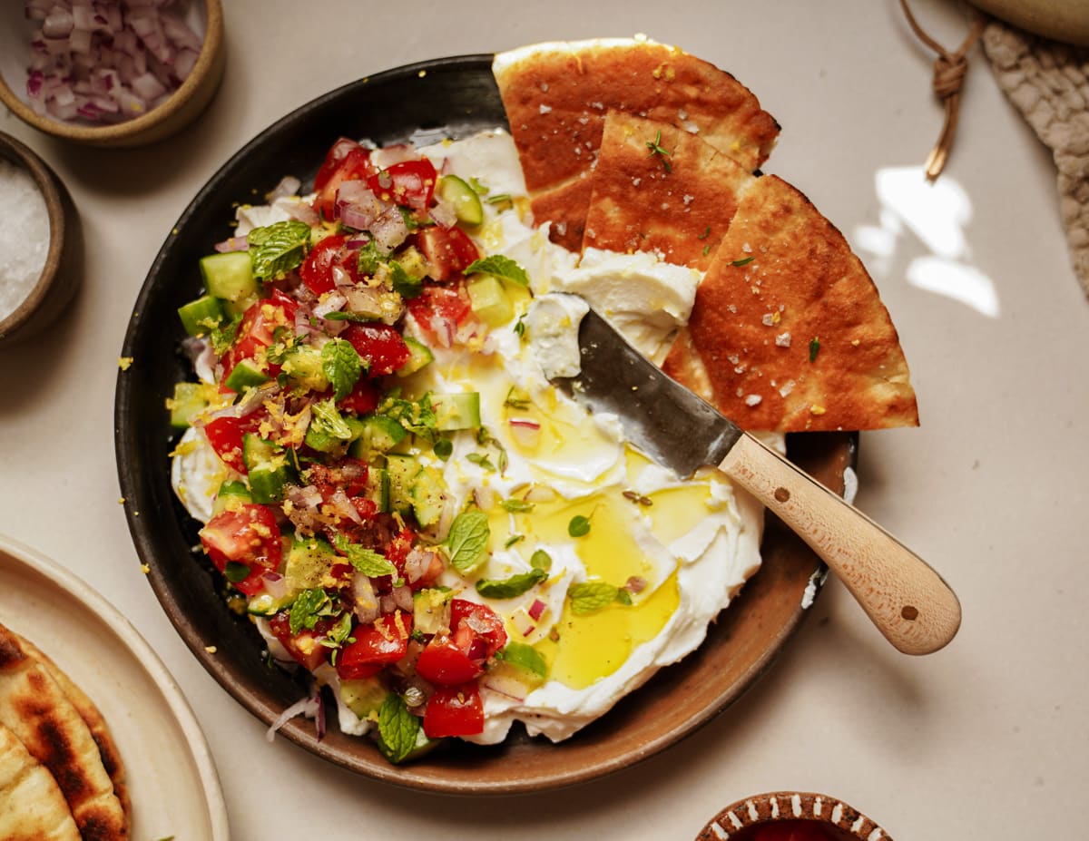 Labneh spread out on a plate with pita bread slices