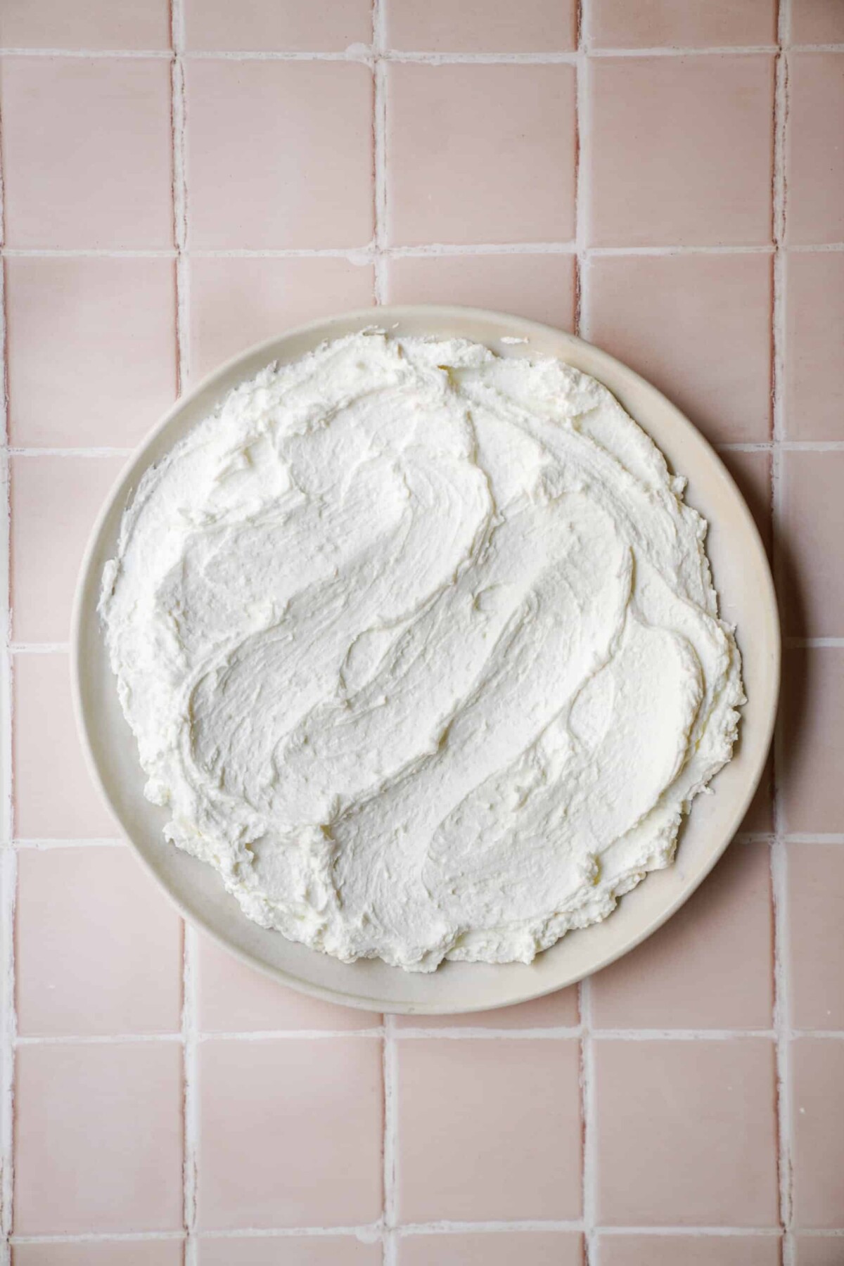 Labneh spread on a plate, and sitting on a counter waiting to be used. 
