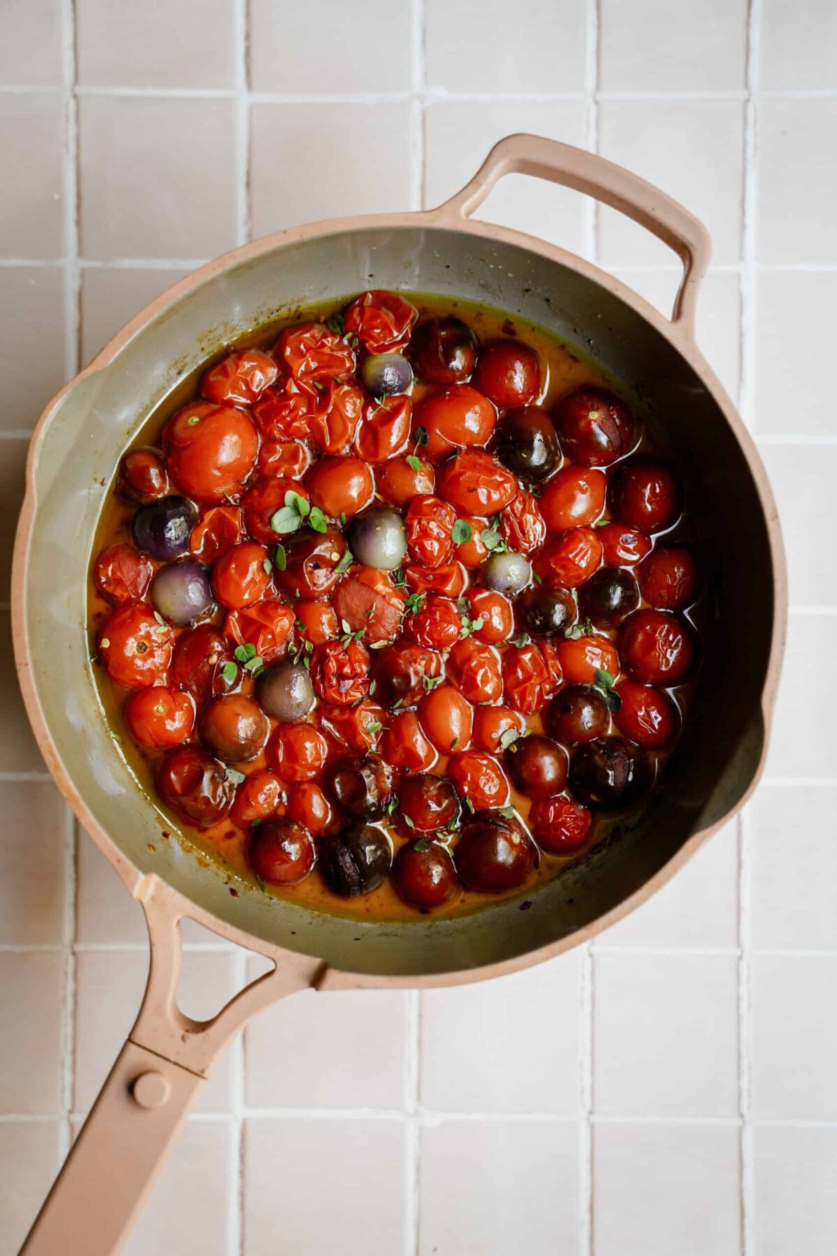 Tomatoes, salt, pepper, fresh herbs and chili pepper flake all cooking in a larget pot.