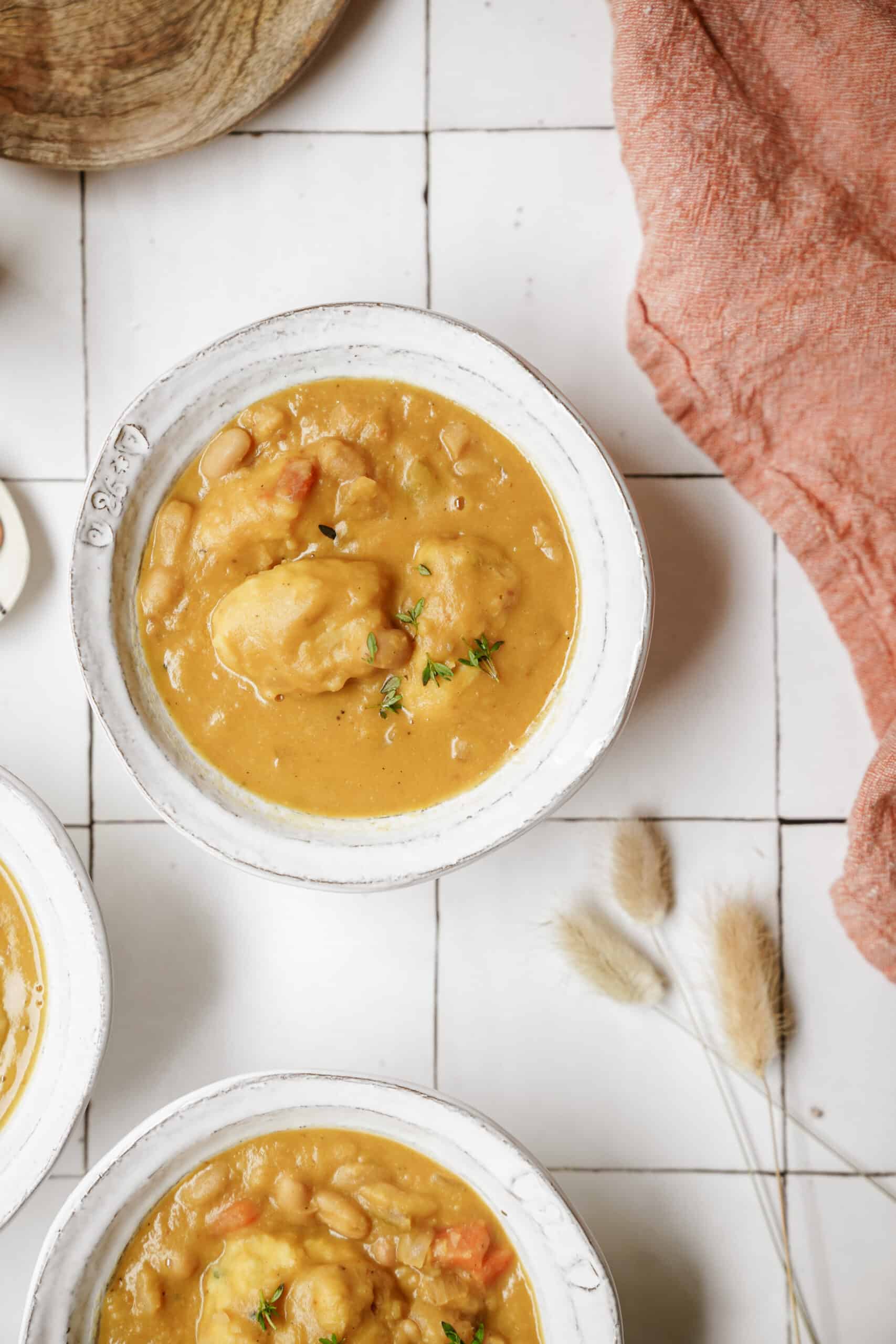 White bean soup with soup dumplings in bowls on countertop 