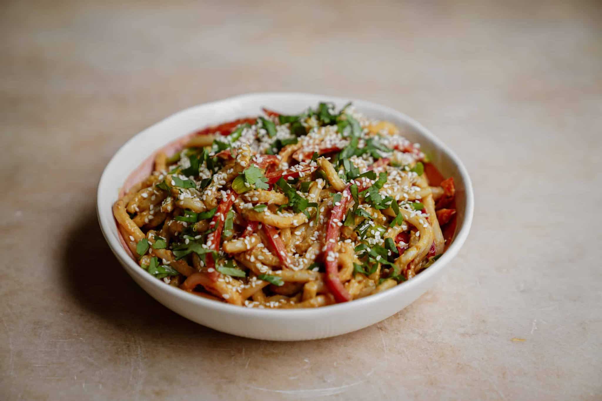 Creamy, spicy udon noodles with peanut sauce in a bowl