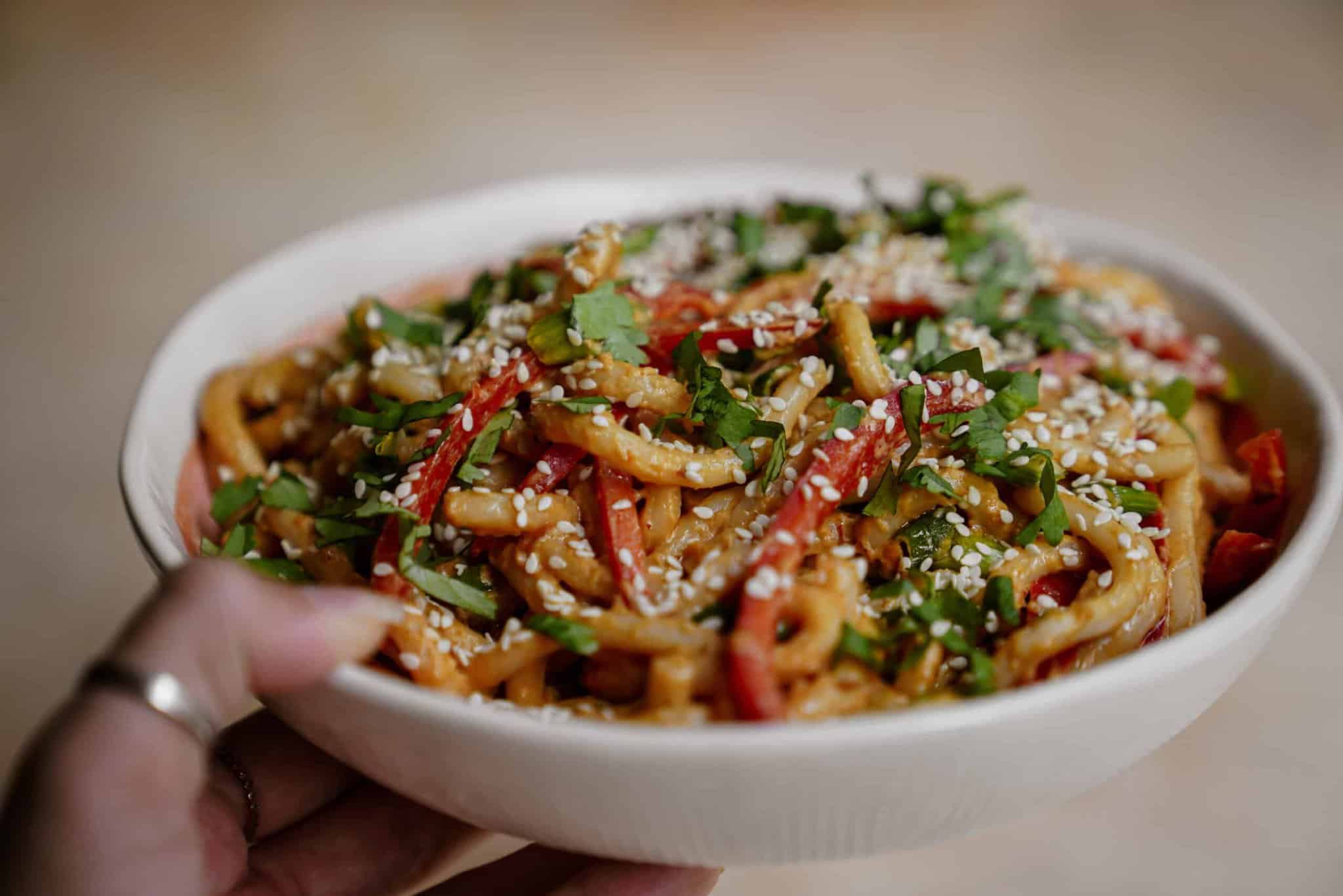 Creamy, spicy udon noodles with peanut sauce in a bowl